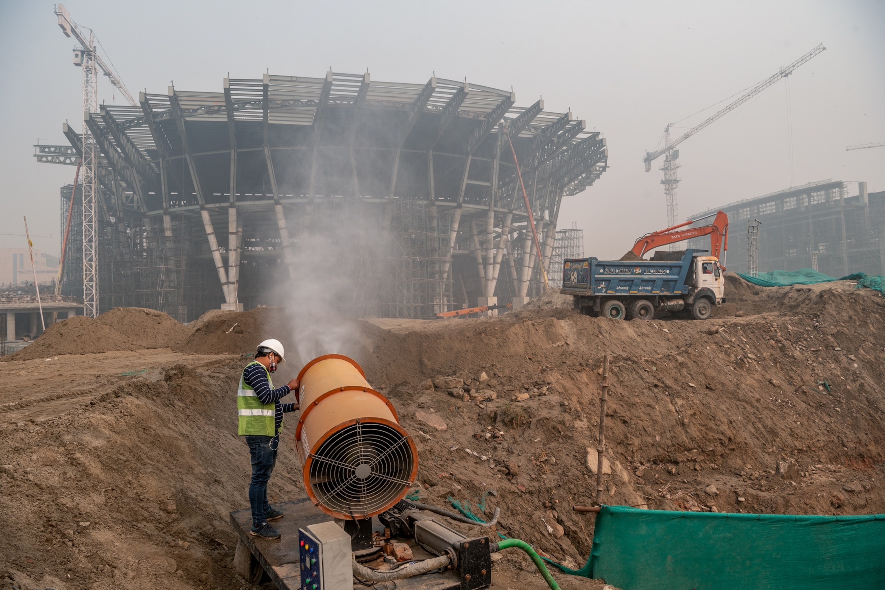 A man tends to a large orange machine spraying mist