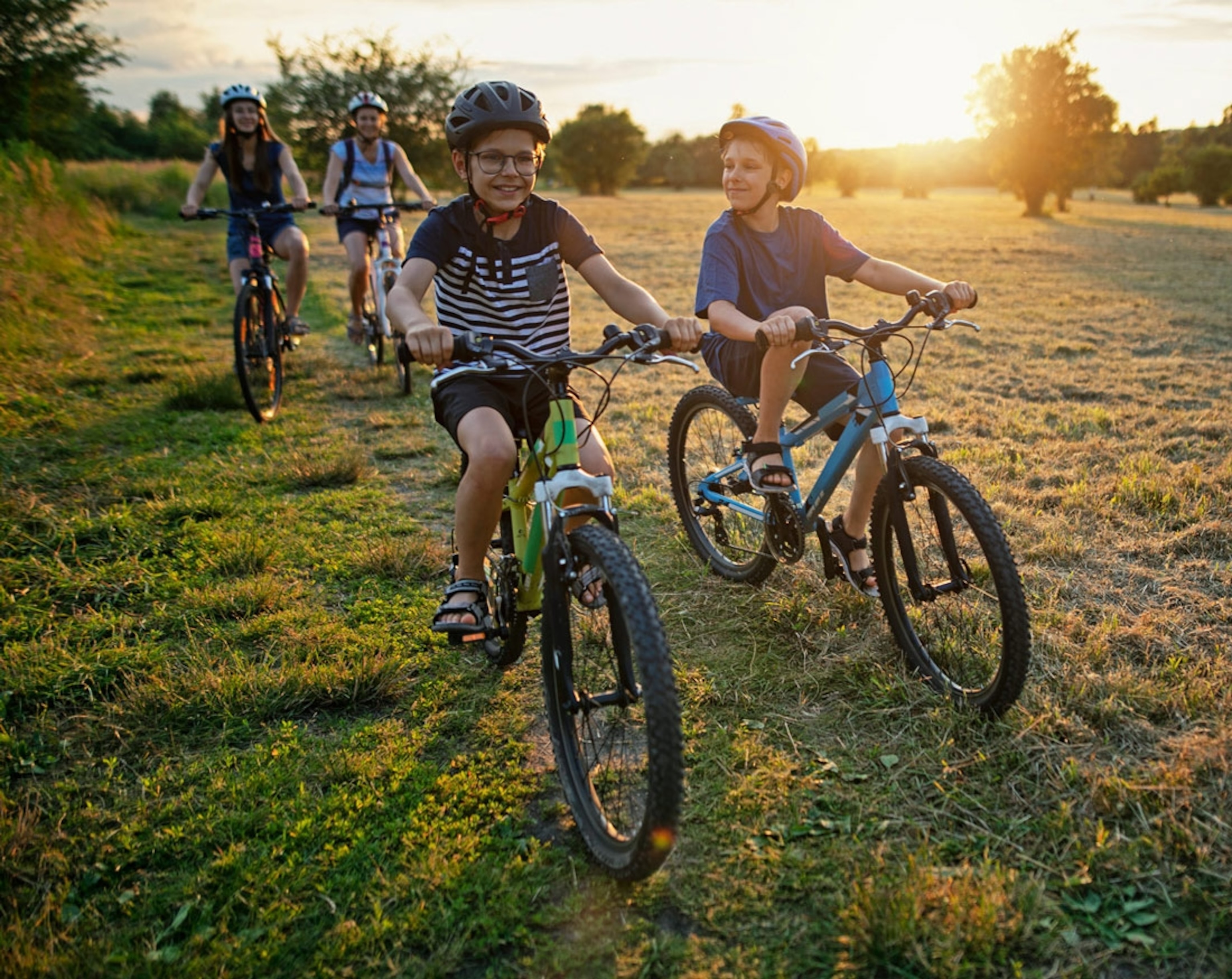 Mother and kids are enjoying a bike trip together. Summer sunset.