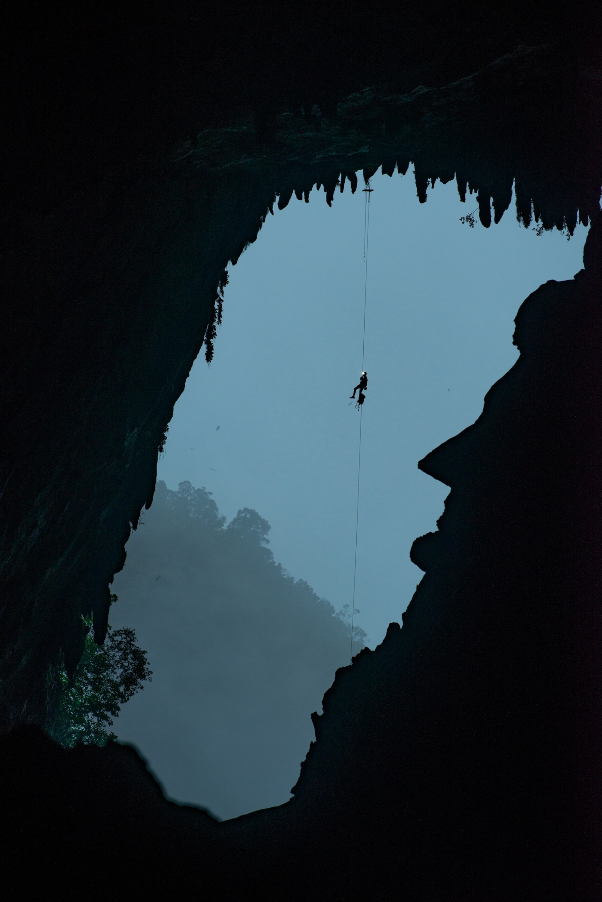 man dangling on a rope above a rock looking like Abraham Lincoln' profile