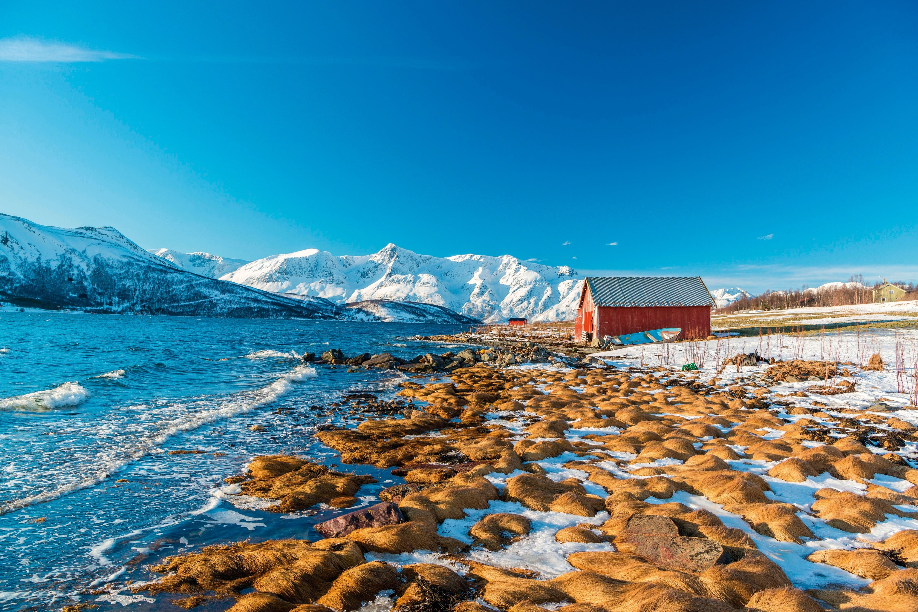 peninsula in winter, featuring shoreline, distant red hut and mountains