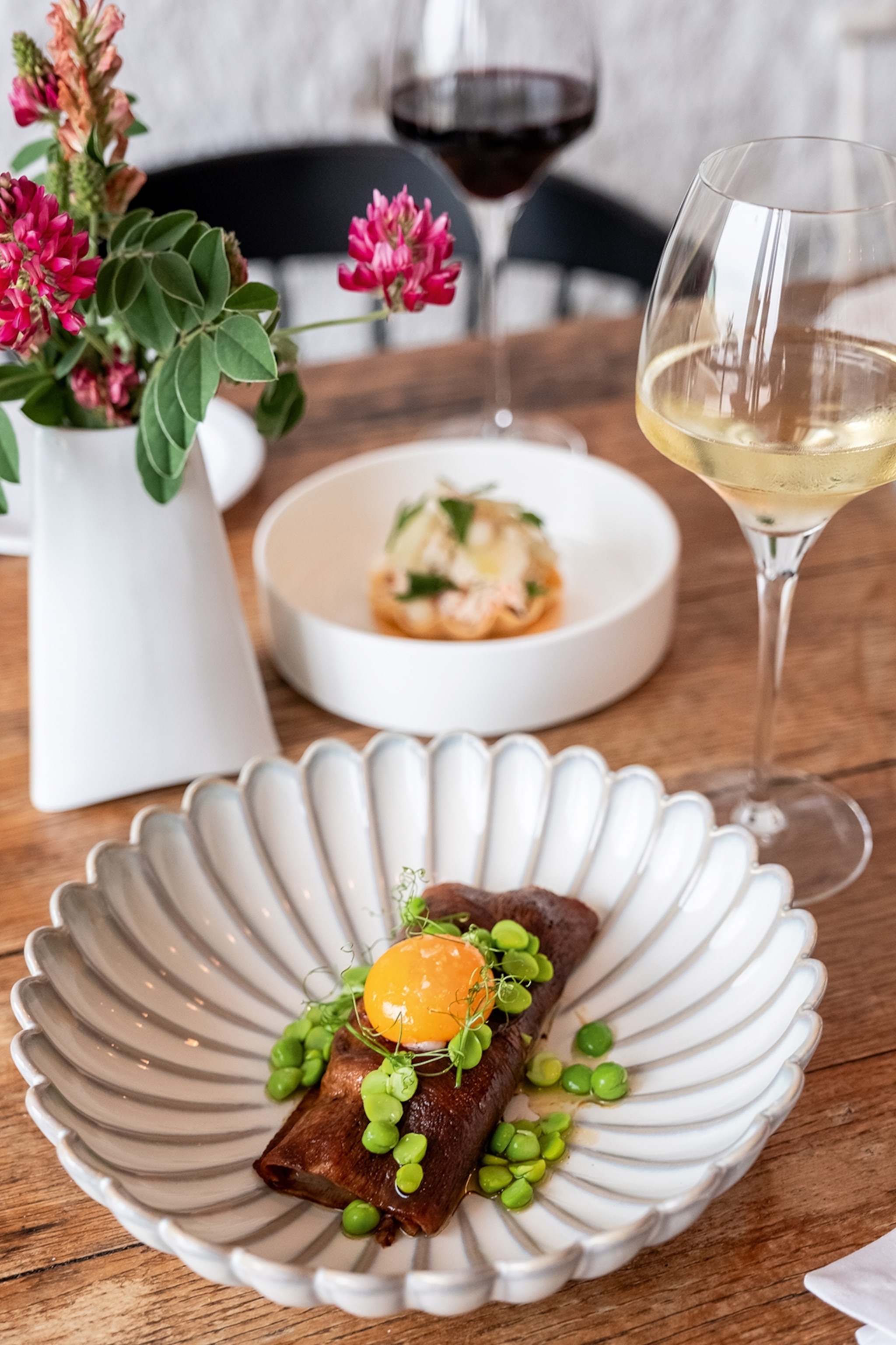 A range of dishes at The Harbour Club restaurant in Valletta. Dishes are served in white bowls - in the foreground a dish of beef tongue with egg yolk is garnished with green herbs.