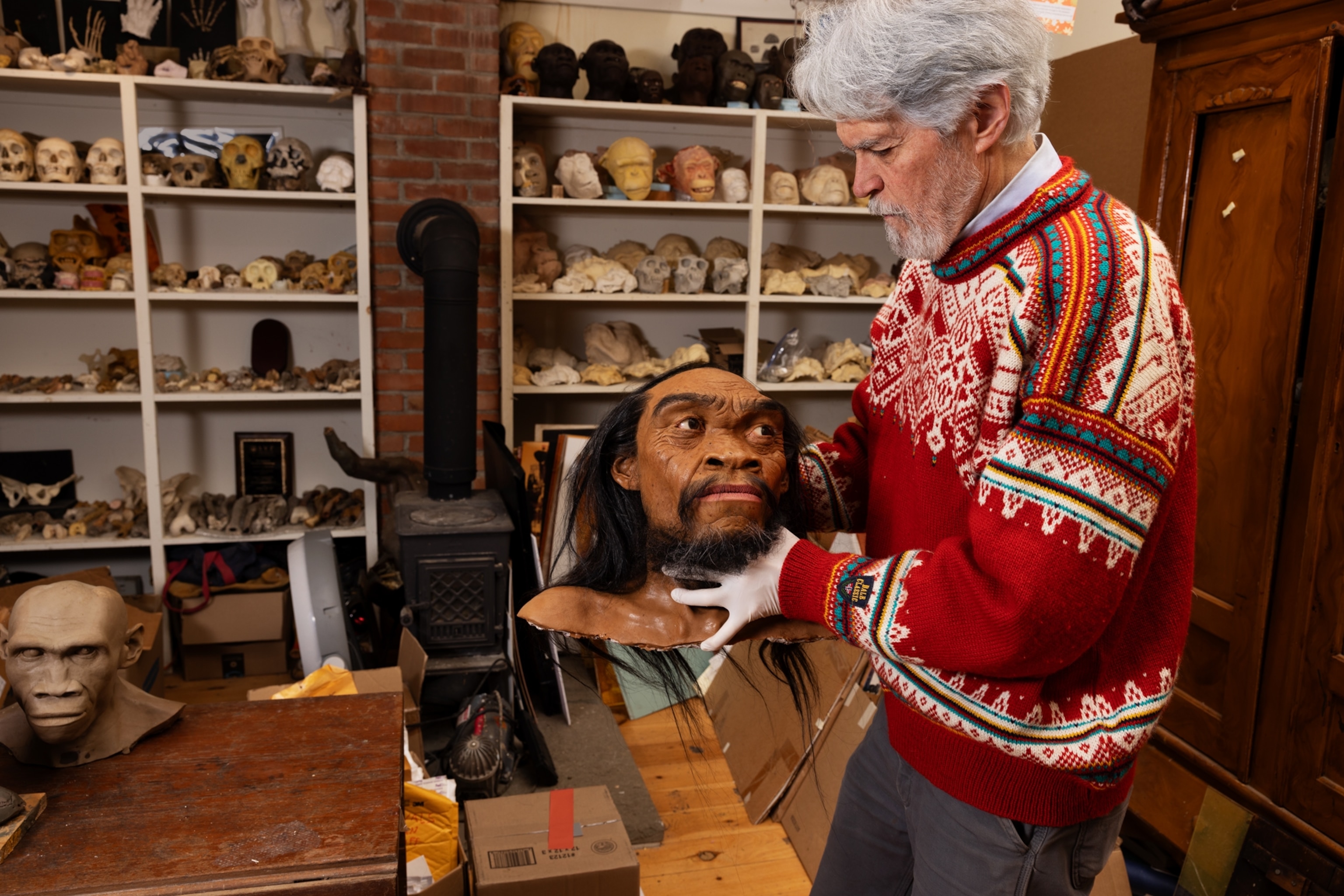 A man holds up the bust of a facial reconstruction.