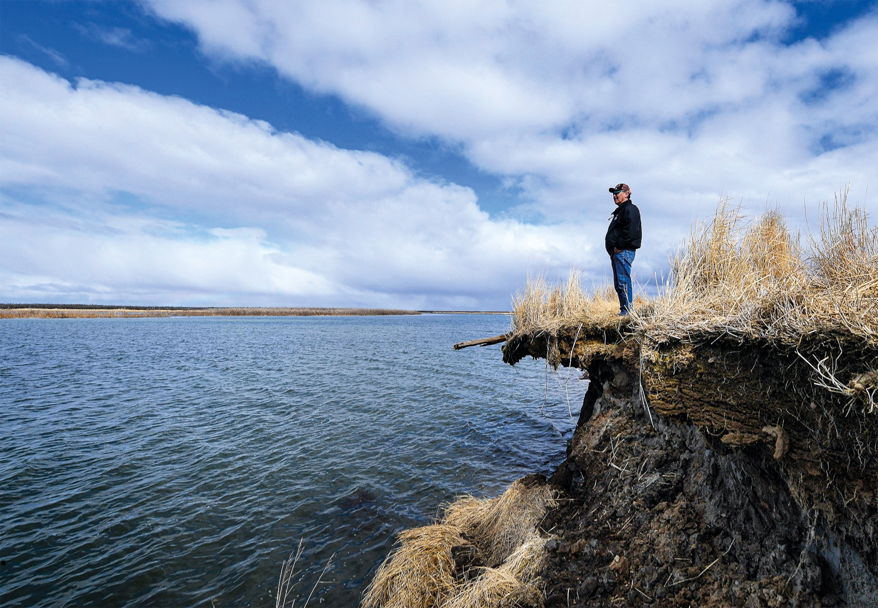 Tribal elder Warren Jones stands where erosion is eating away at Yup’ik lands in southwest Alaska. Permafrost and sea ice once formed a protective barrier, but warming temperatures have wreaked havoc on local waterways.