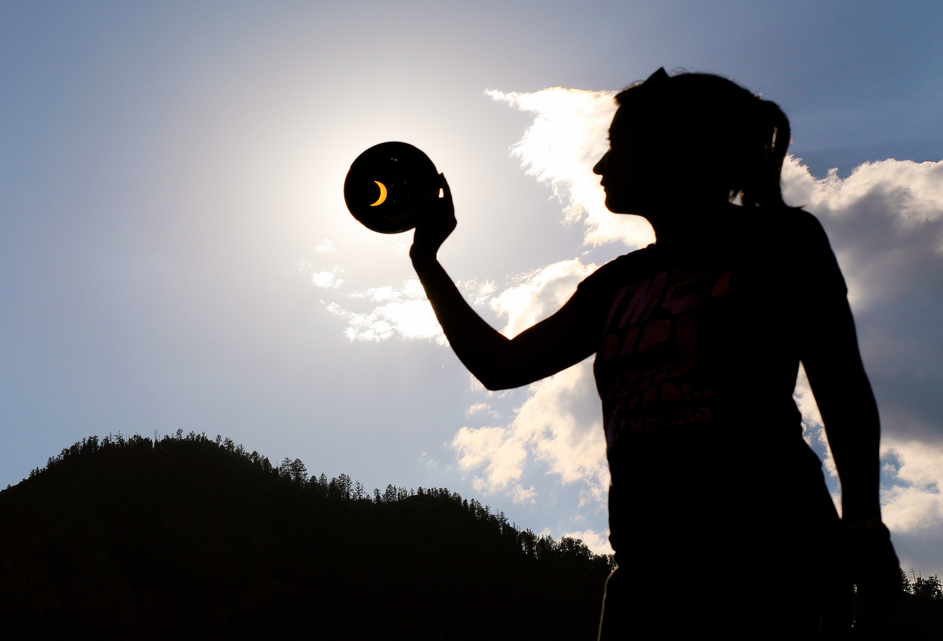 woman holding a filter over the partially eclipsed sun in Siberia, Russia