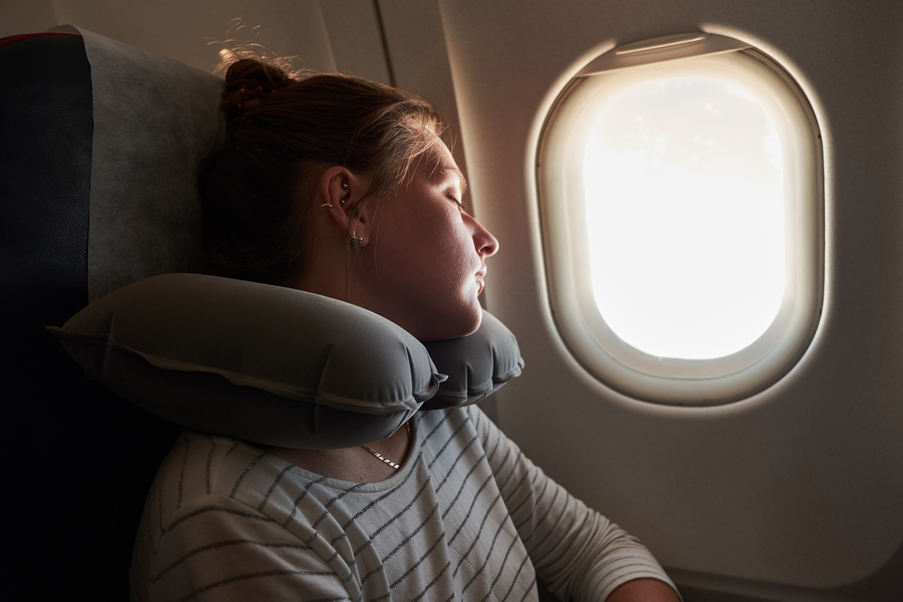 A girl is illuminated by light near a window.