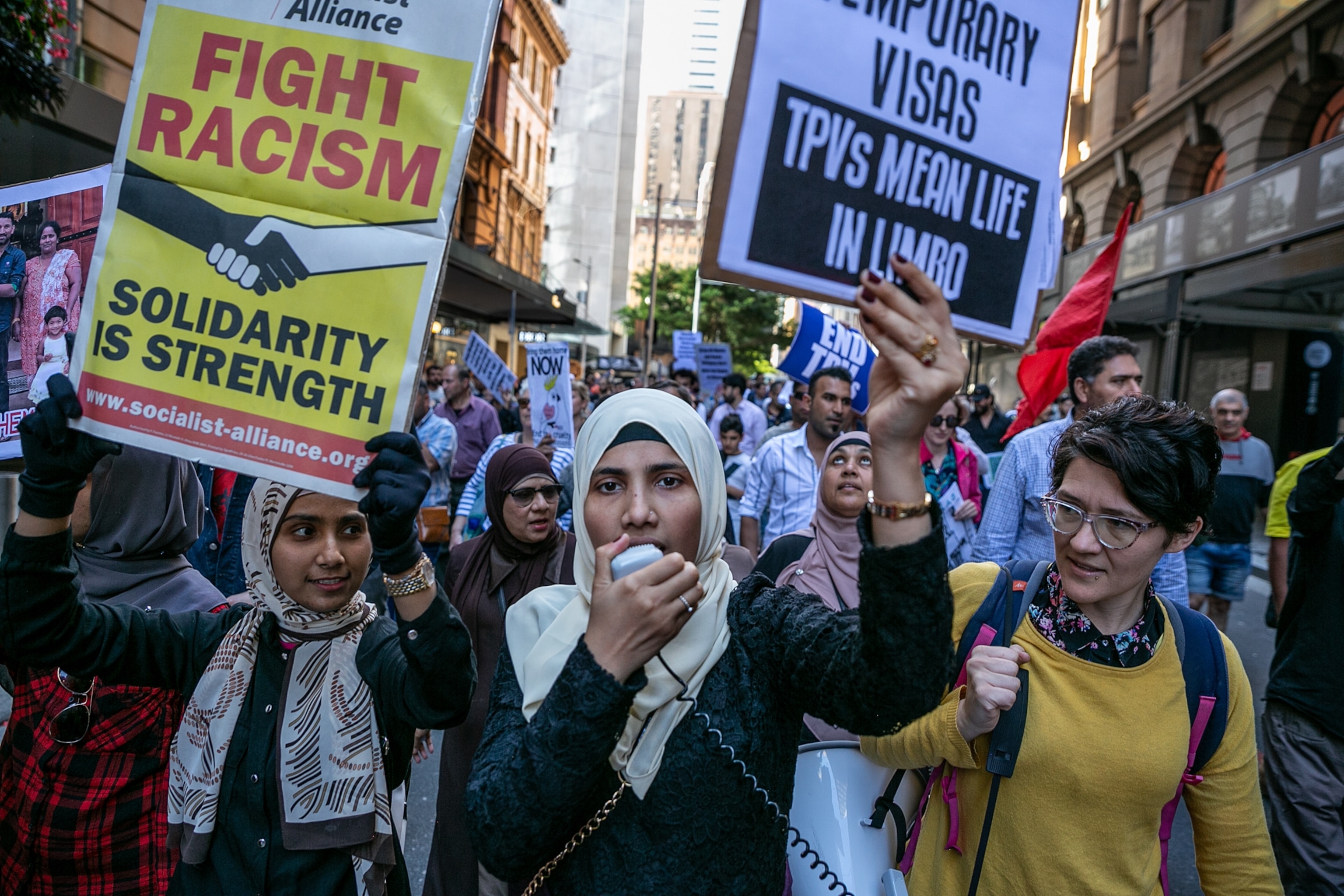 a woman holding a sign and a hand microphone while at a protest