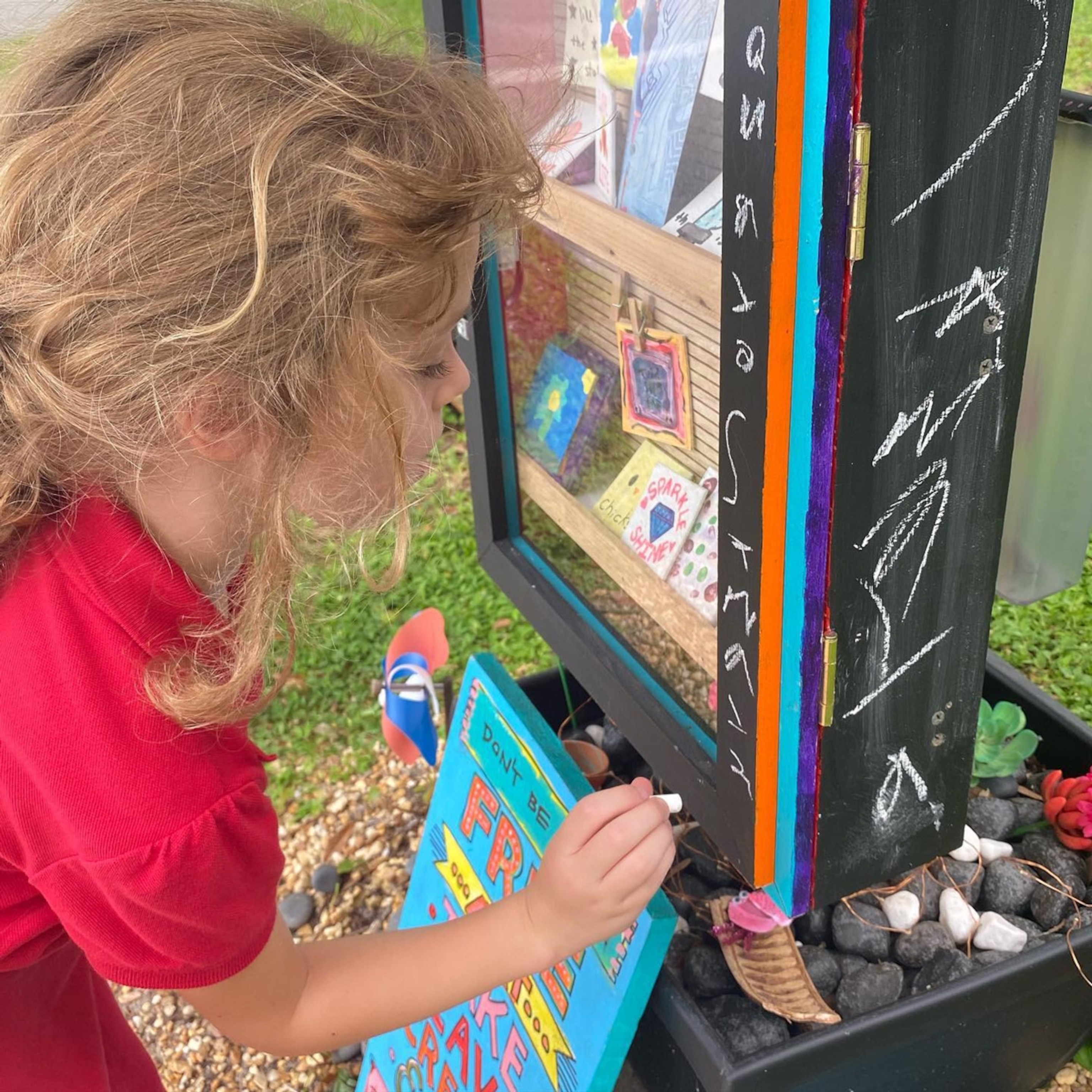 Samaya Laeger, age 6 writing a note in chalk on the Free Little Art Gallery of Sarasota, FL.