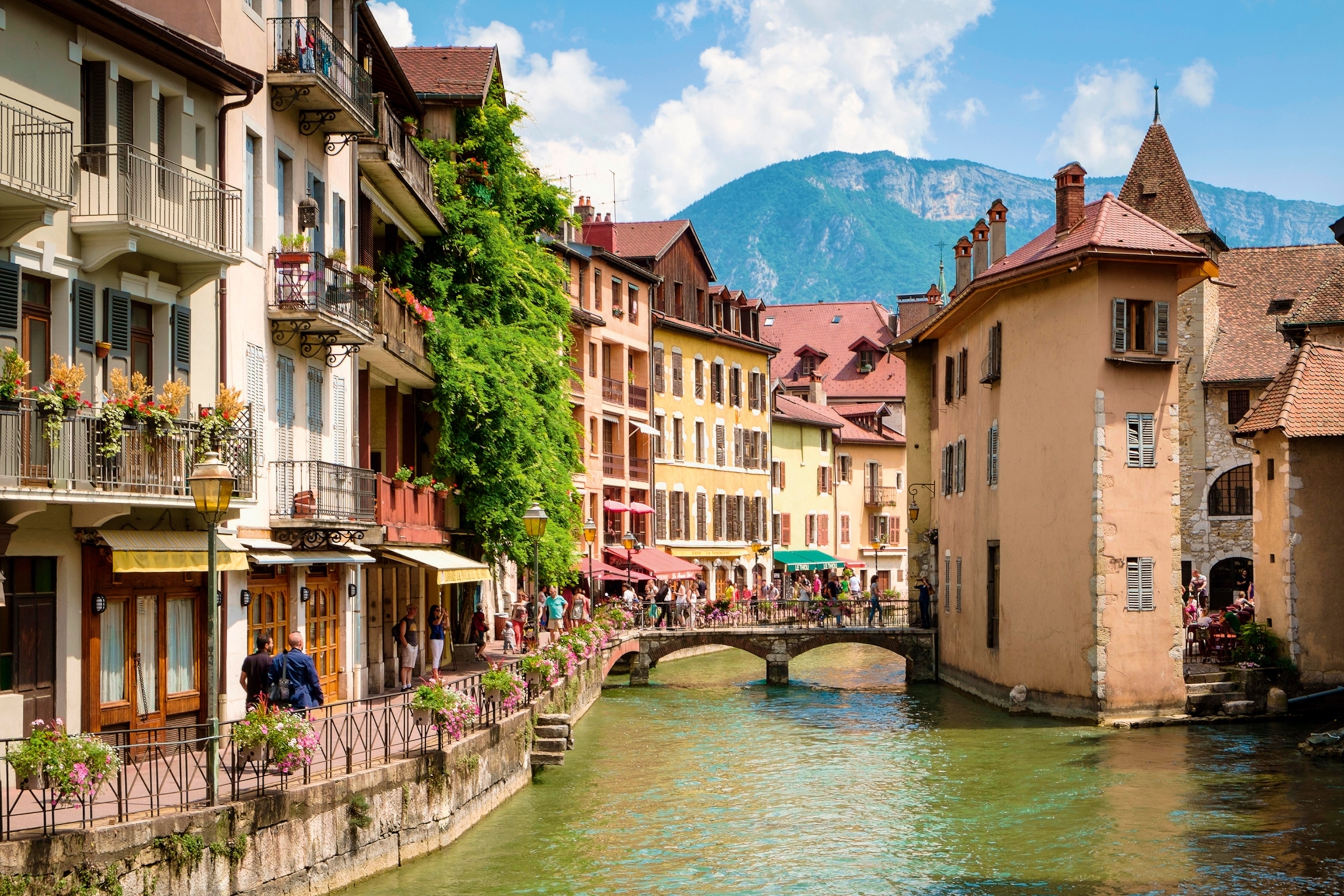 An old French village with quaint multicolored houses in sunset shades, and a mountain in the far background.