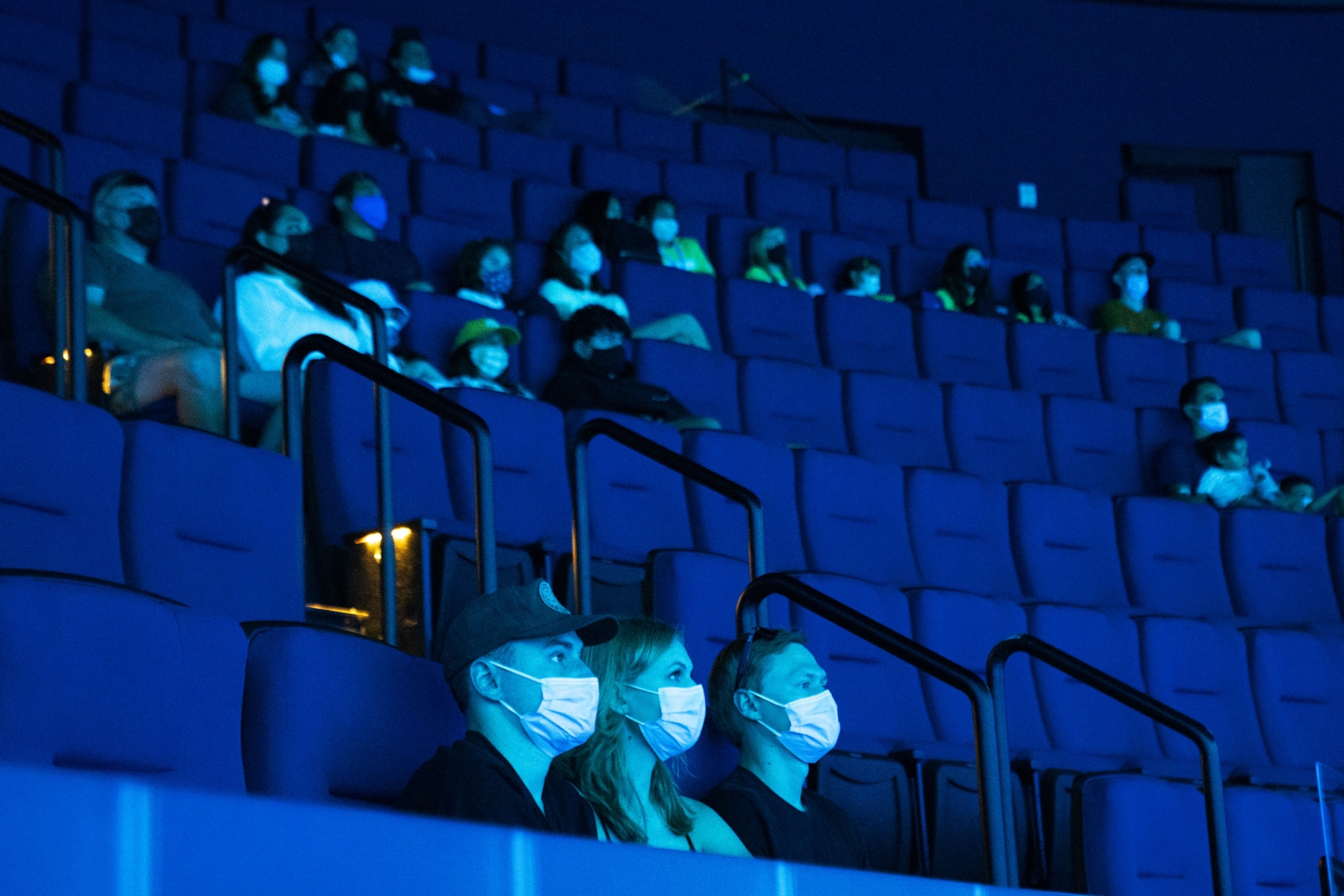 Visitors wearing protective masks watch a film inside a theater at the Aquarium of the Pacific in California.