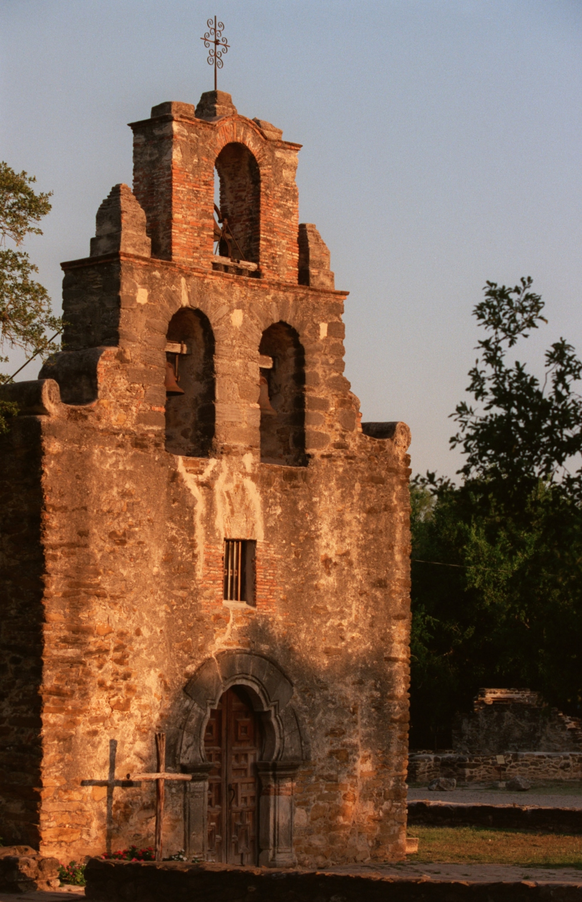 The first rays of sunrise fall across the facade of the tiny church at Mission Espada in San Antonio