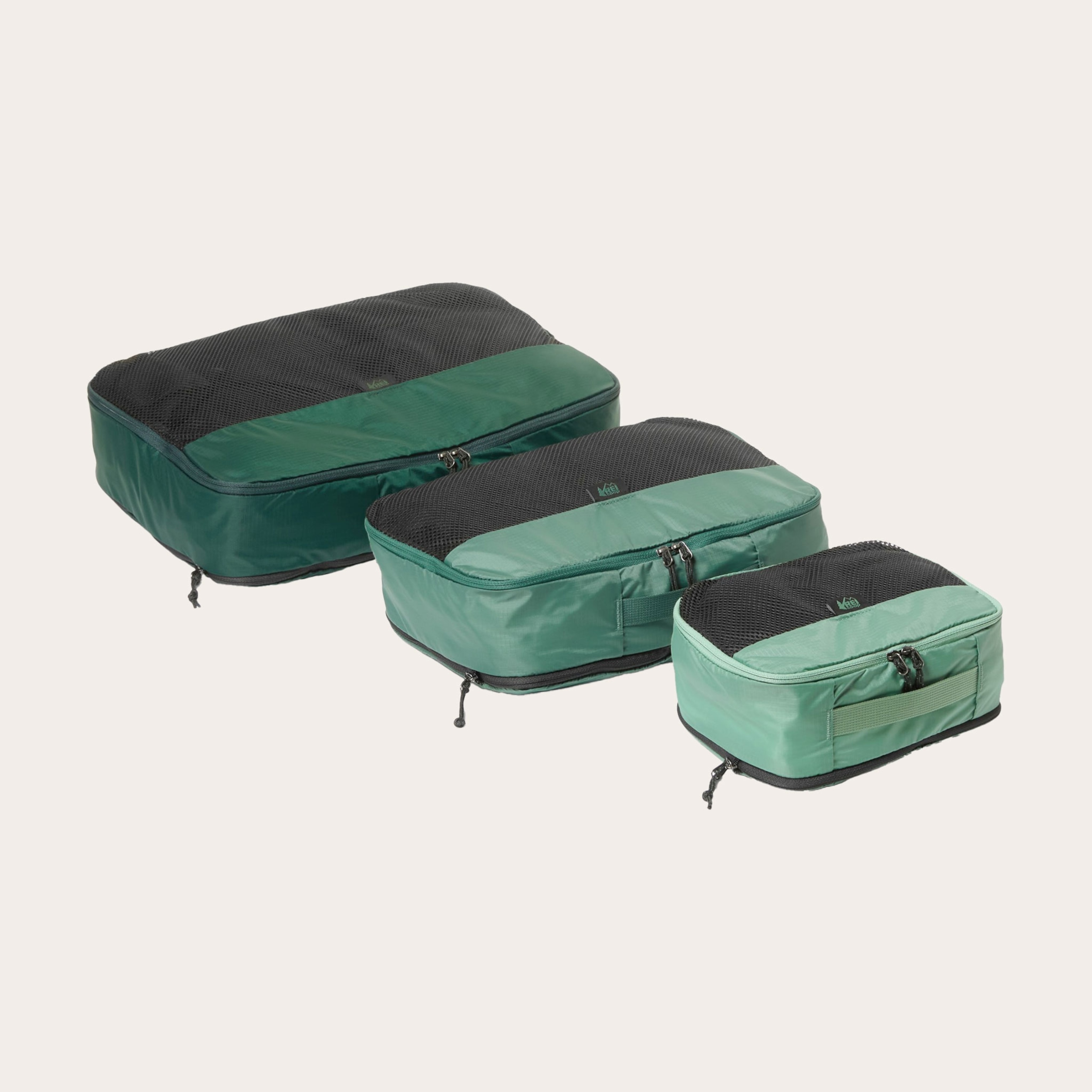 Three green packing cubes lined in row from smallest to biggest.