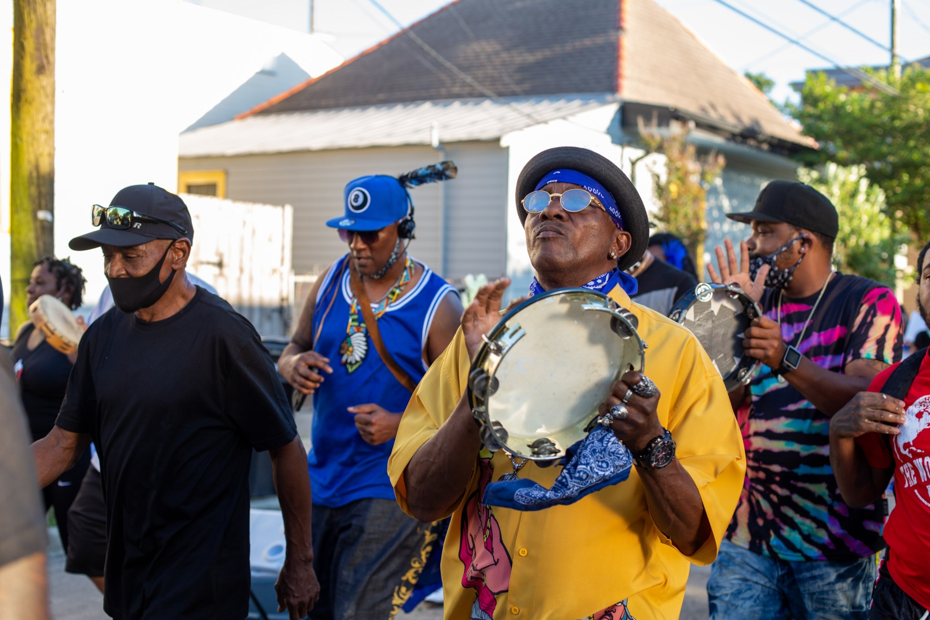 a group of men parading down a street, while the man in front plays tambourine