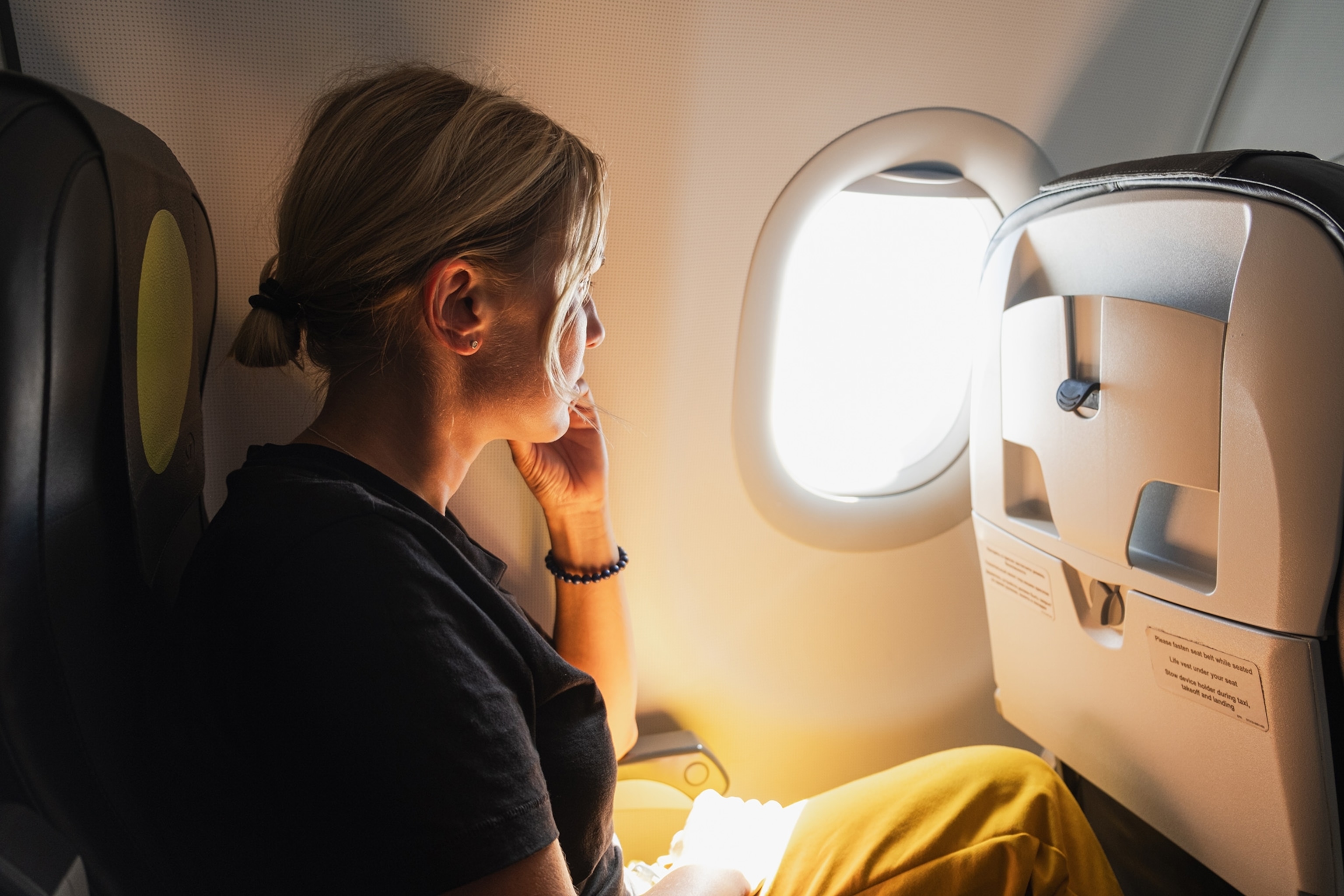 Passenger woman is flying in plane and looking out the window.