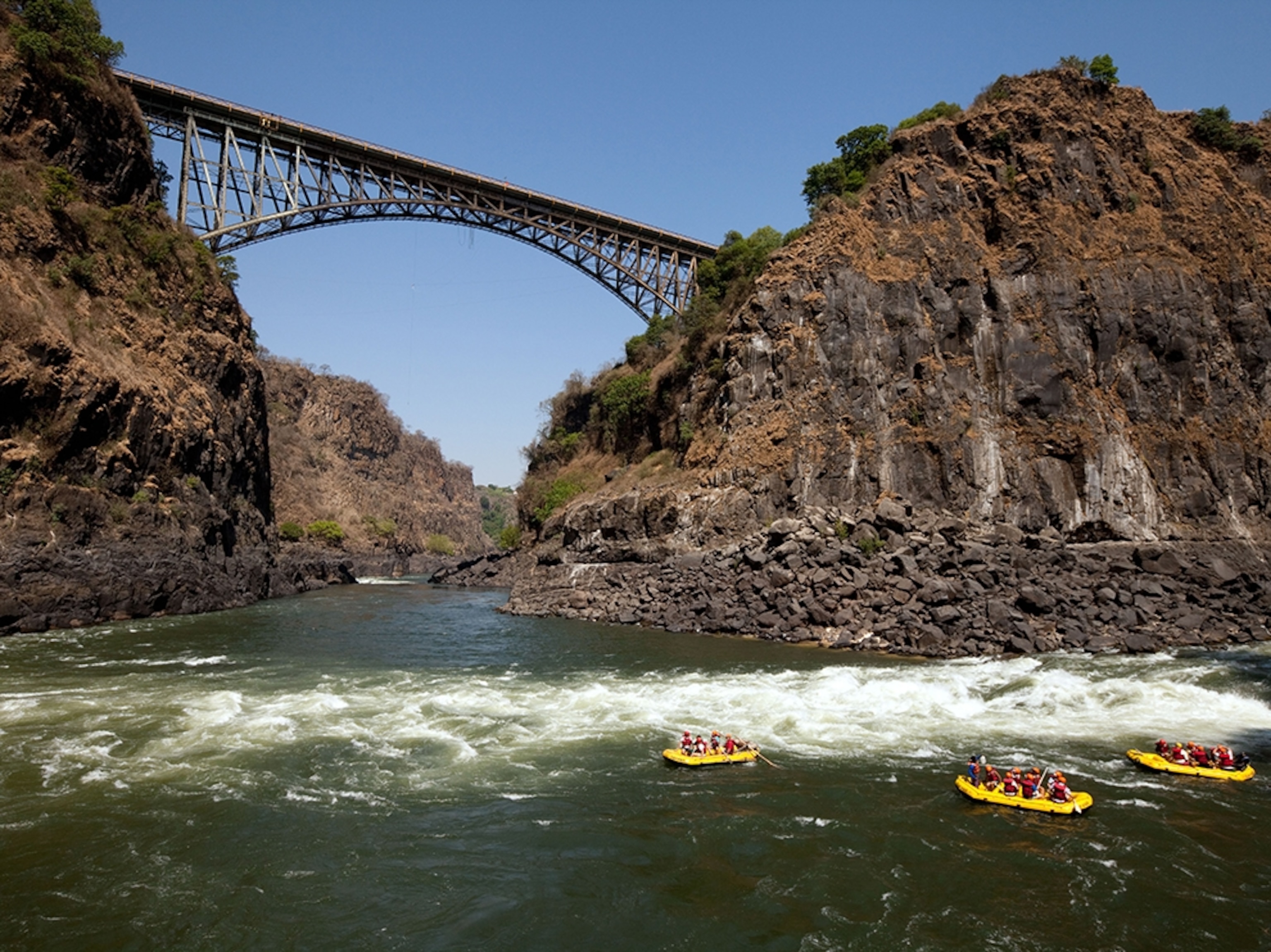 rafters on the Zambezi River in front of Victoria Falls Bridge