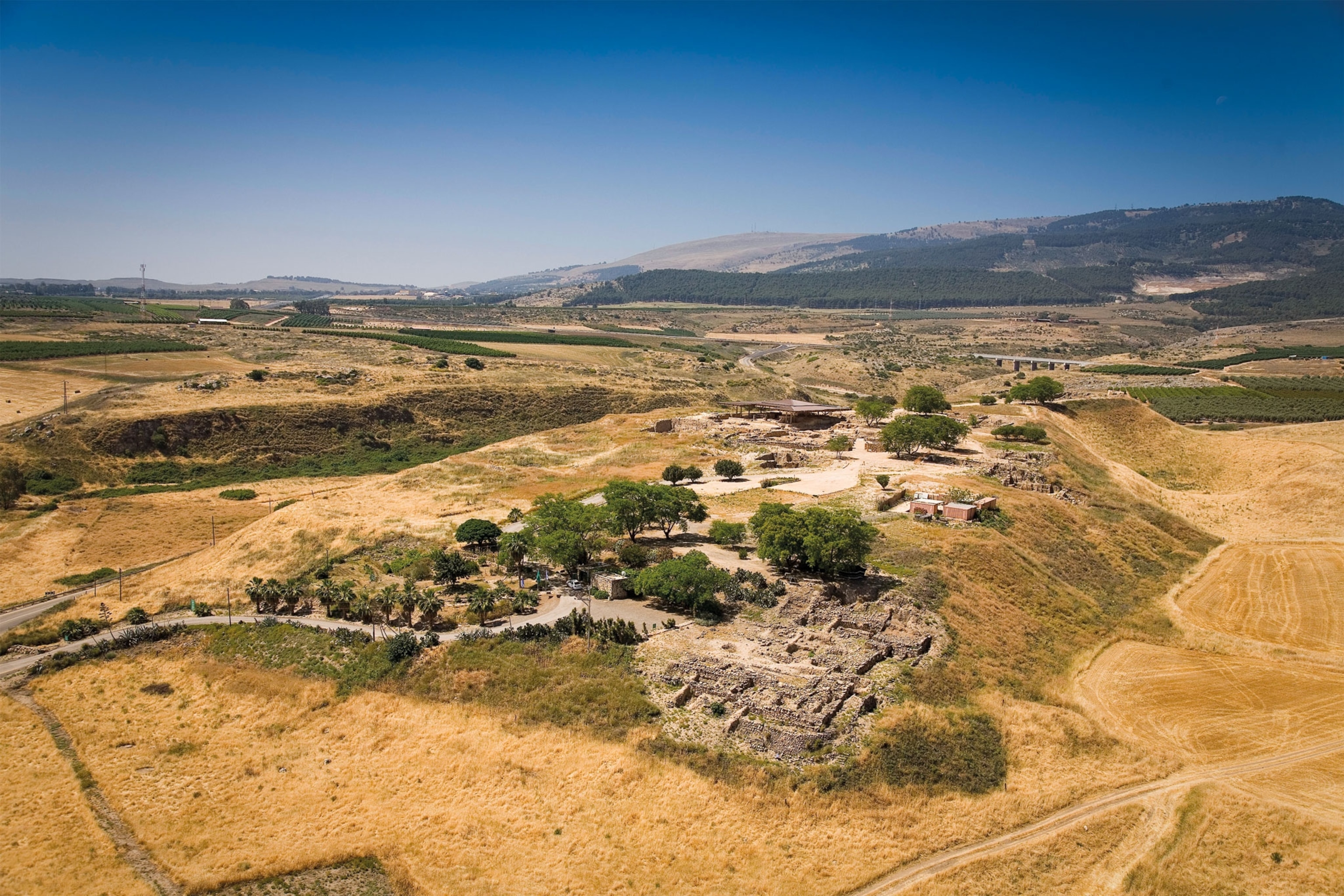 An aerial view of ruins surrounded by low golden hills