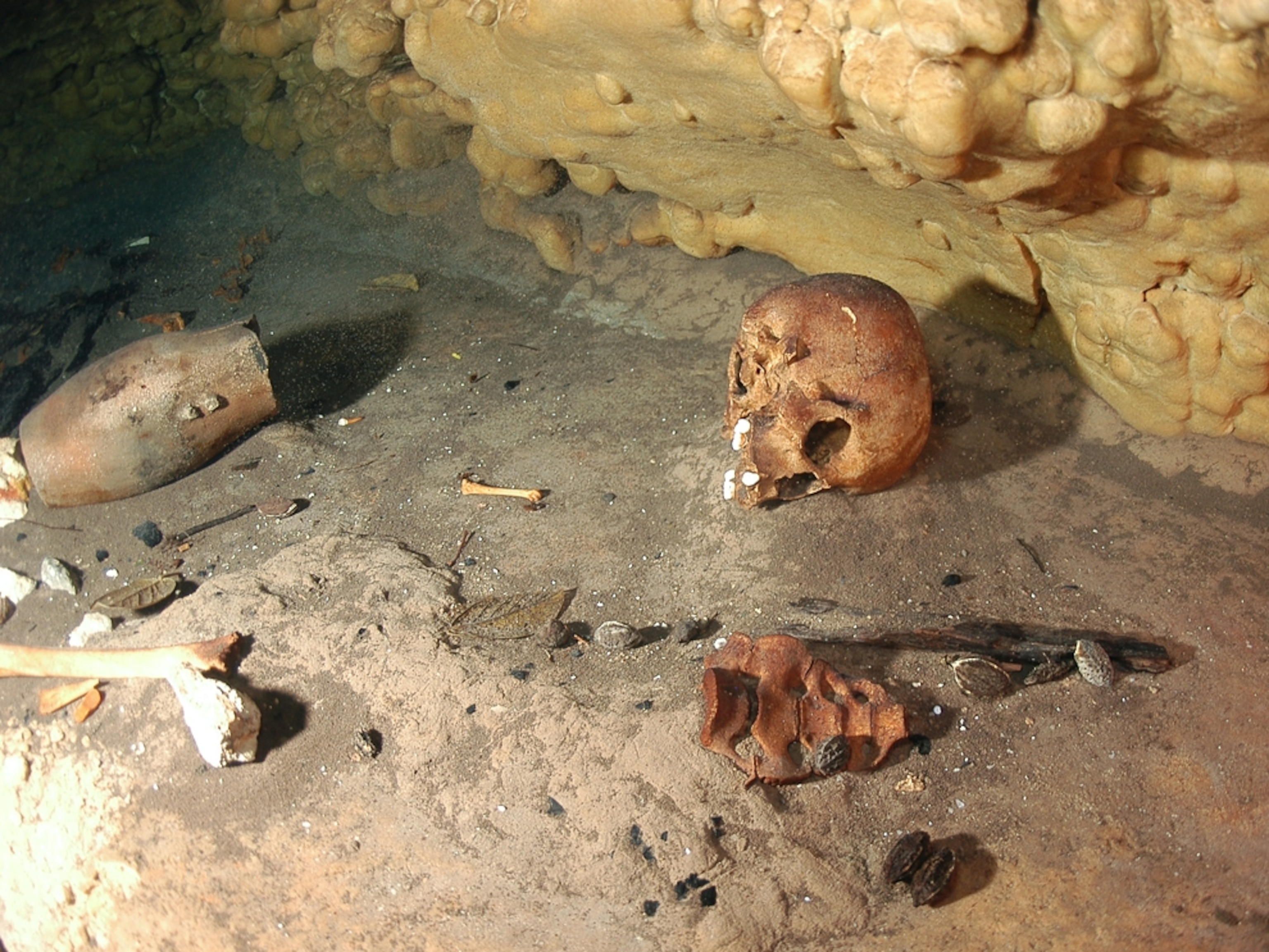 Maya sacrifice picture: A skull and artifacts on a cenote ledge