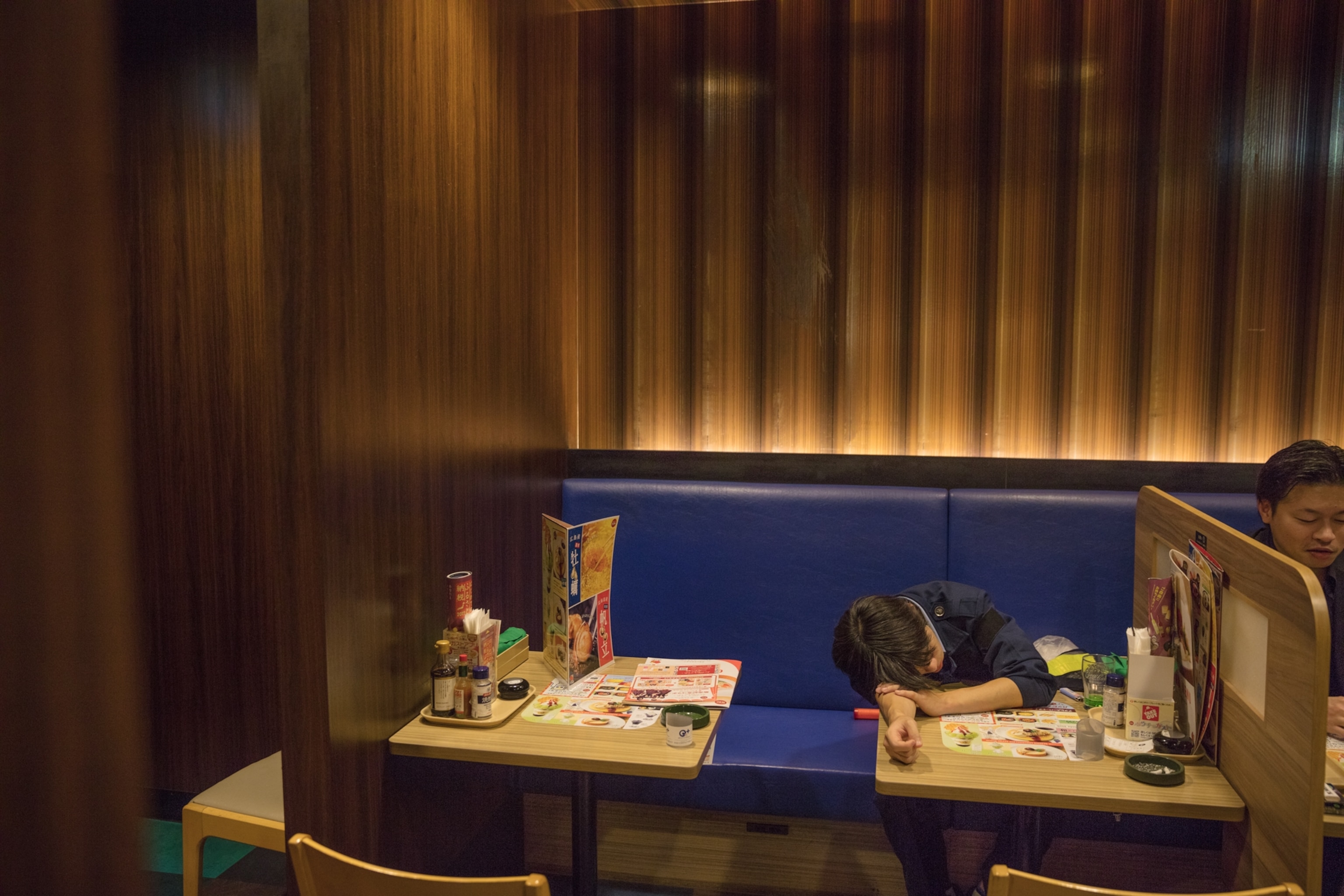 a man sleeping with his head rested on a table in a restaurant
