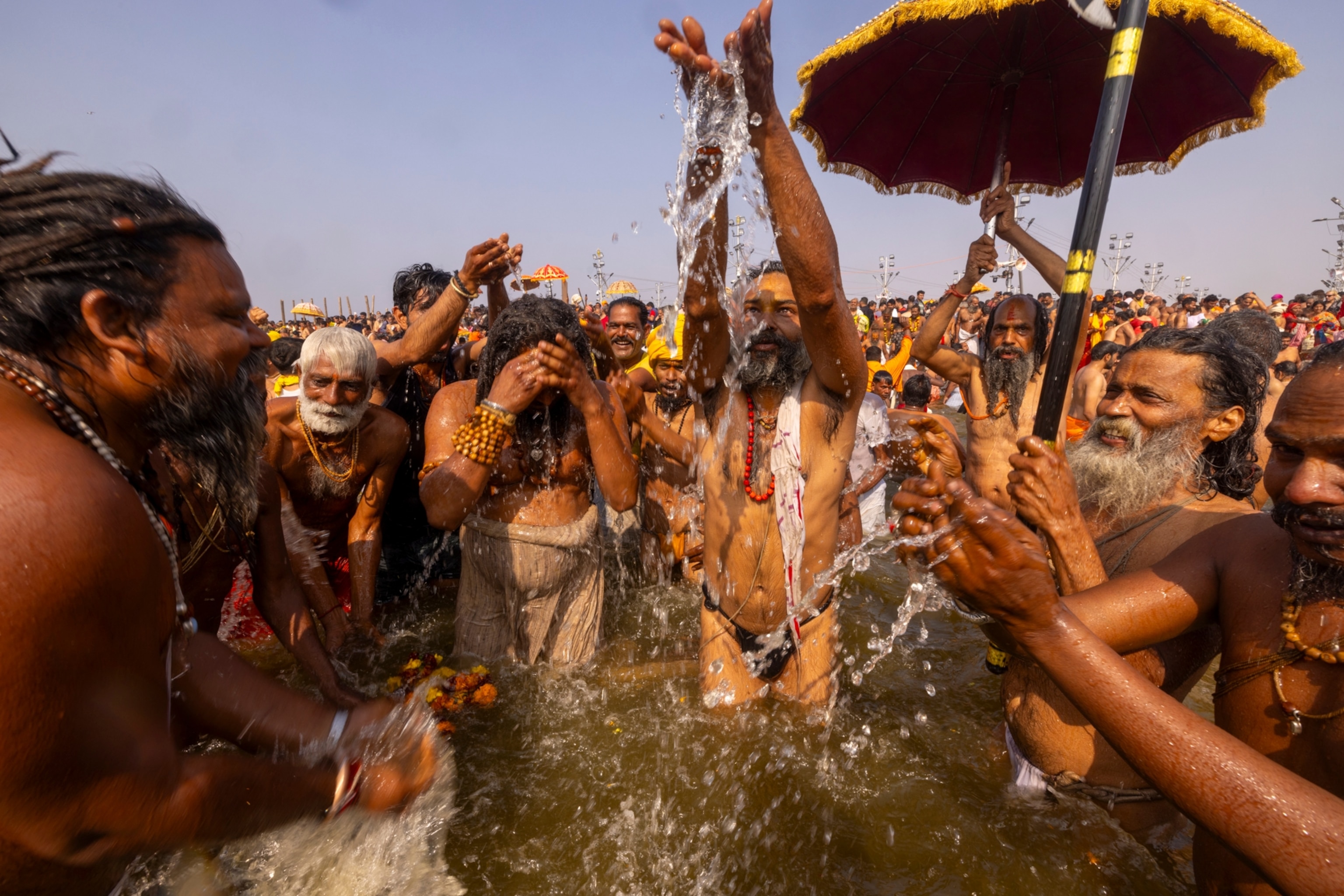 People stand in a river and throw water into the air.