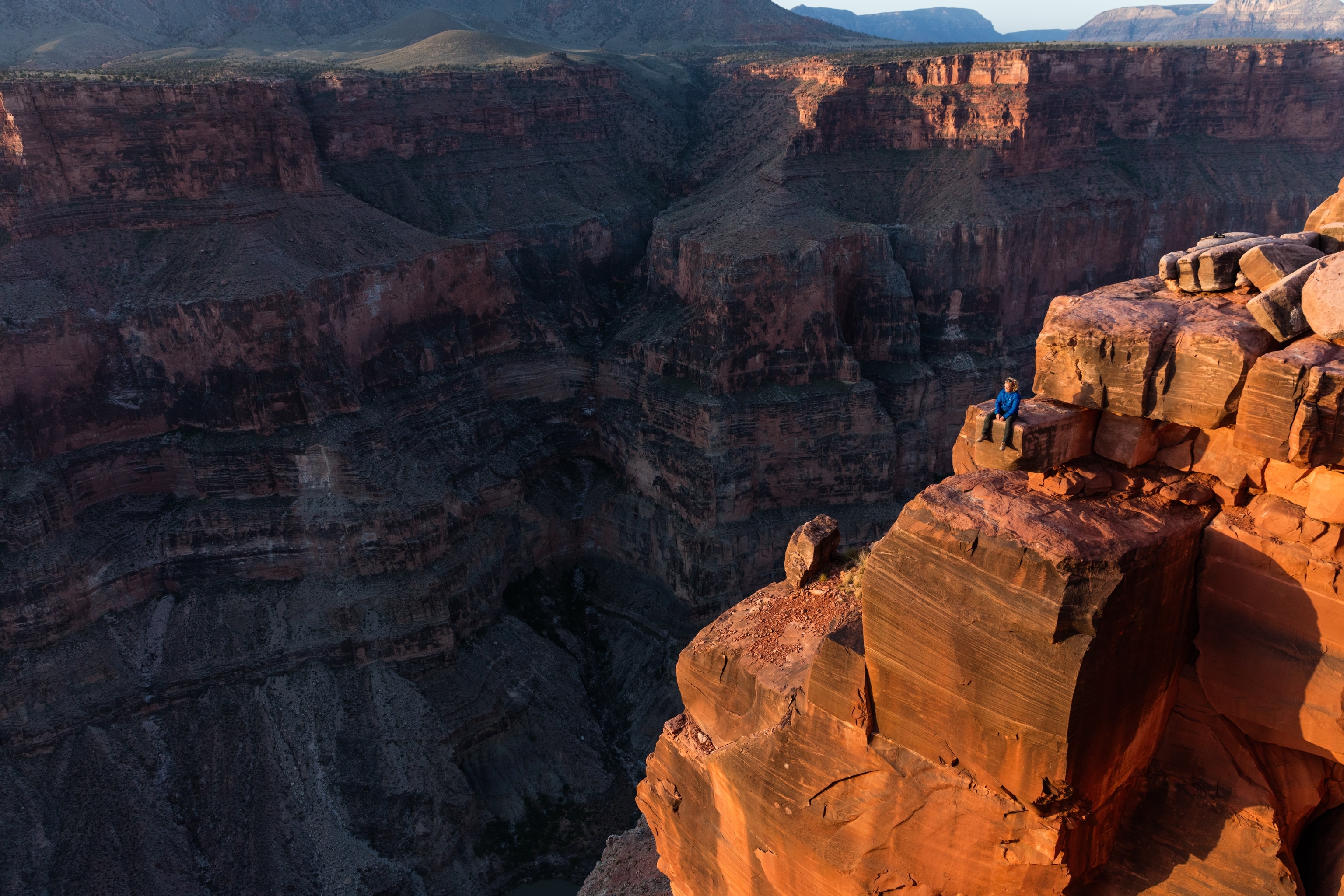 A hiker enjoys the sunrise from Toroweap Point above the Colorado River.
