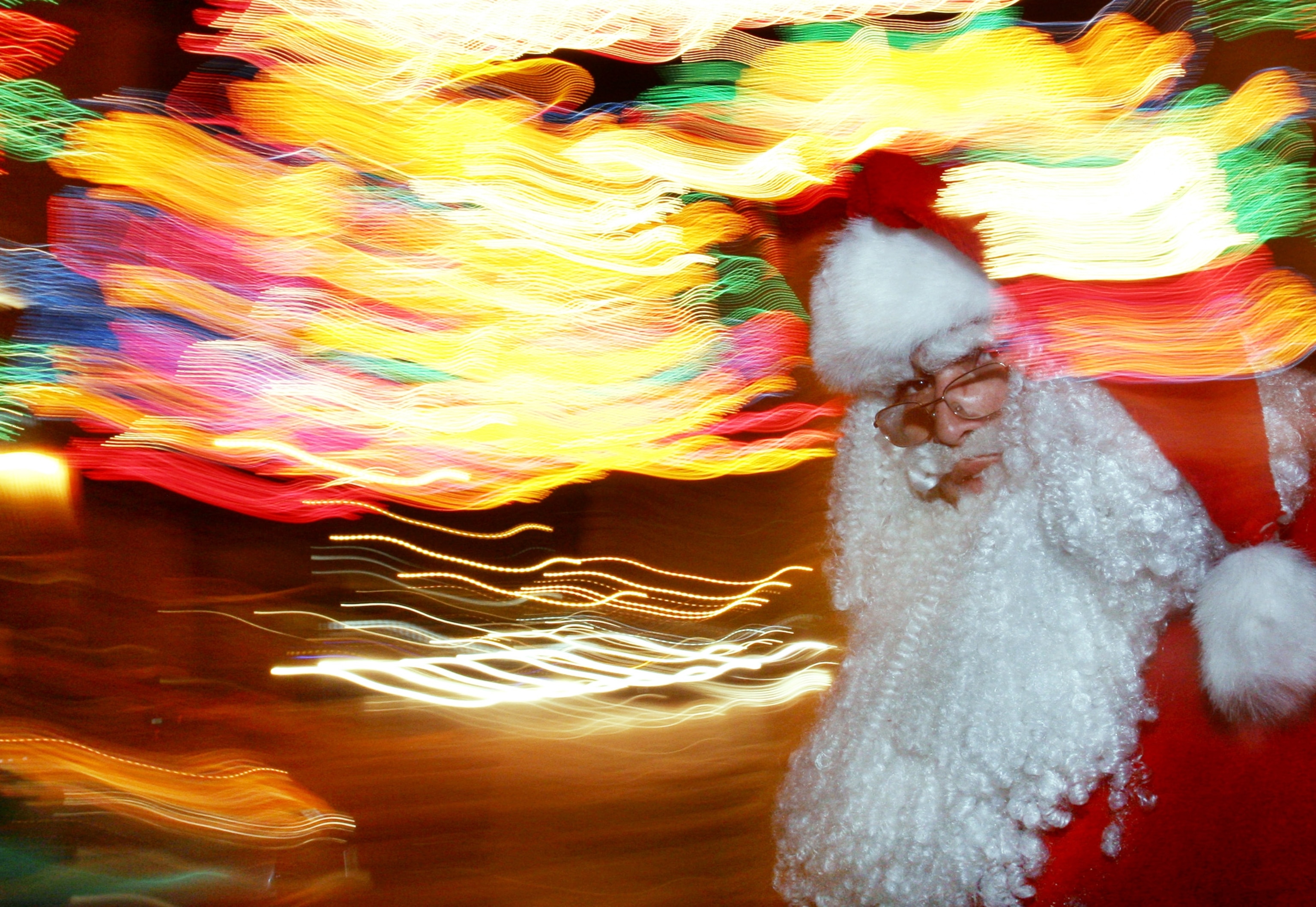 a man dressed as Santa Claus with blurred busy city lights