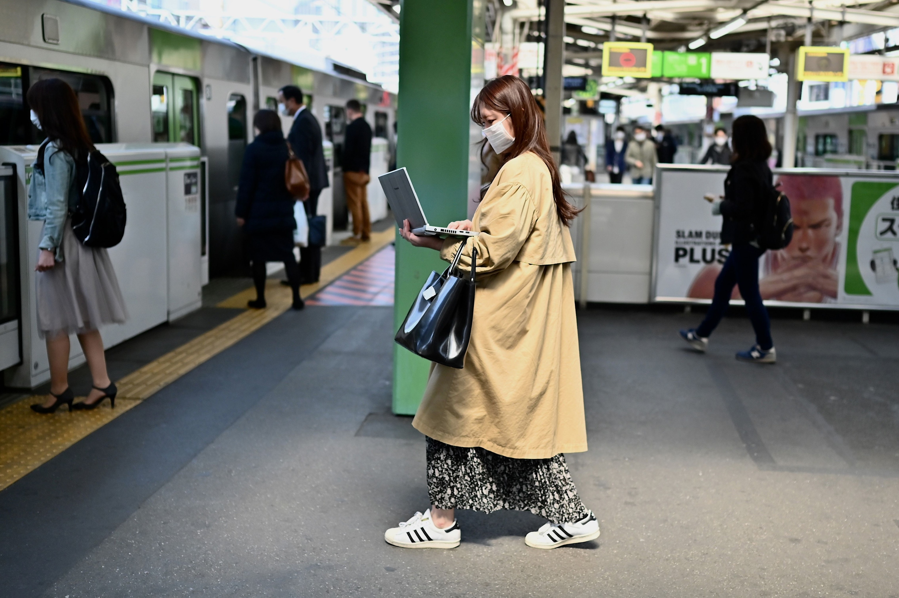 A woman works on her laptop computer while entering a train at Gotanda train station in Tokyo
