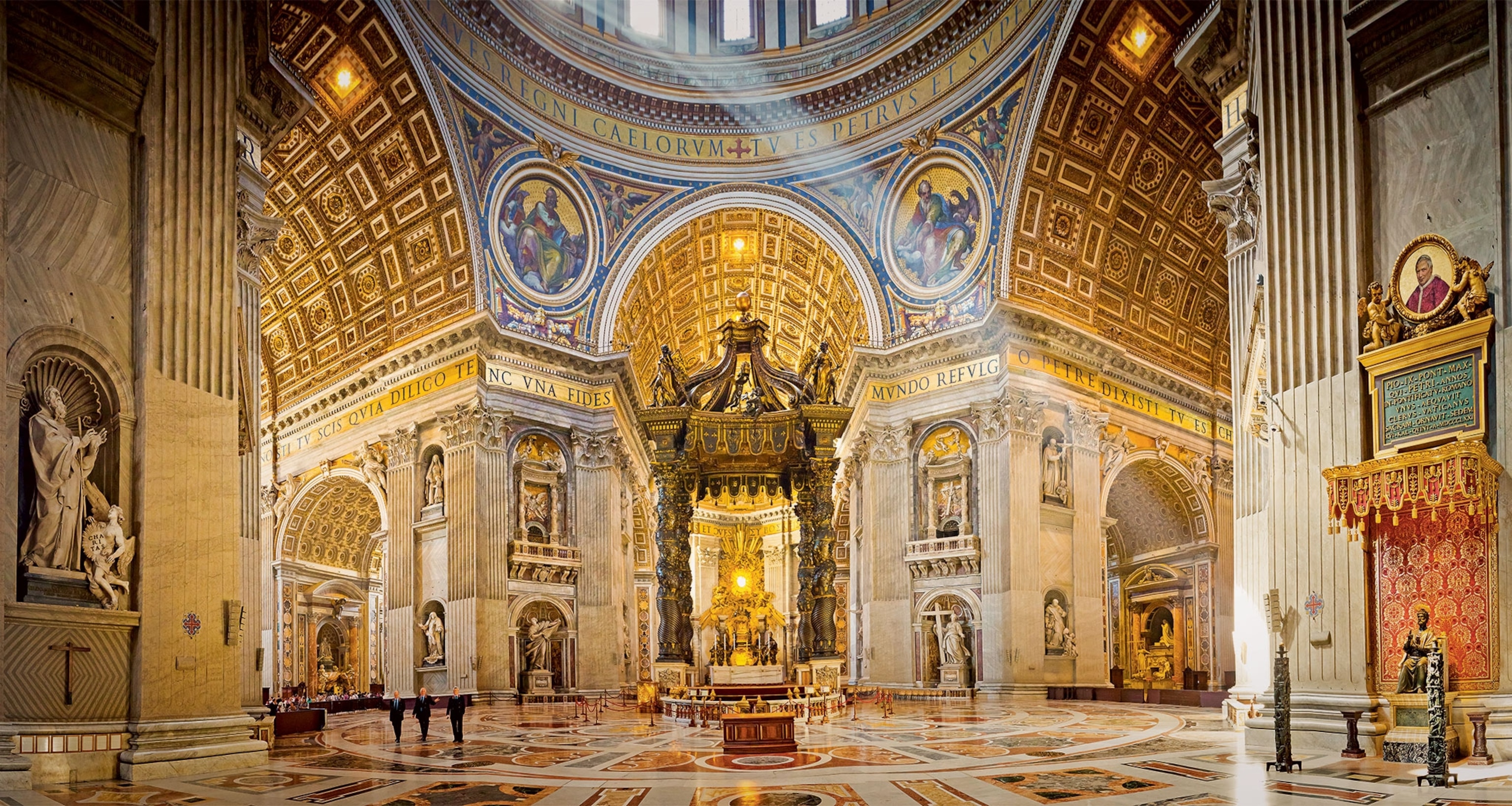 A wide view of the Basilica of St. Peter at the Vatican, with Michelangelo's painted dome, golden trim, several statues, and an altar