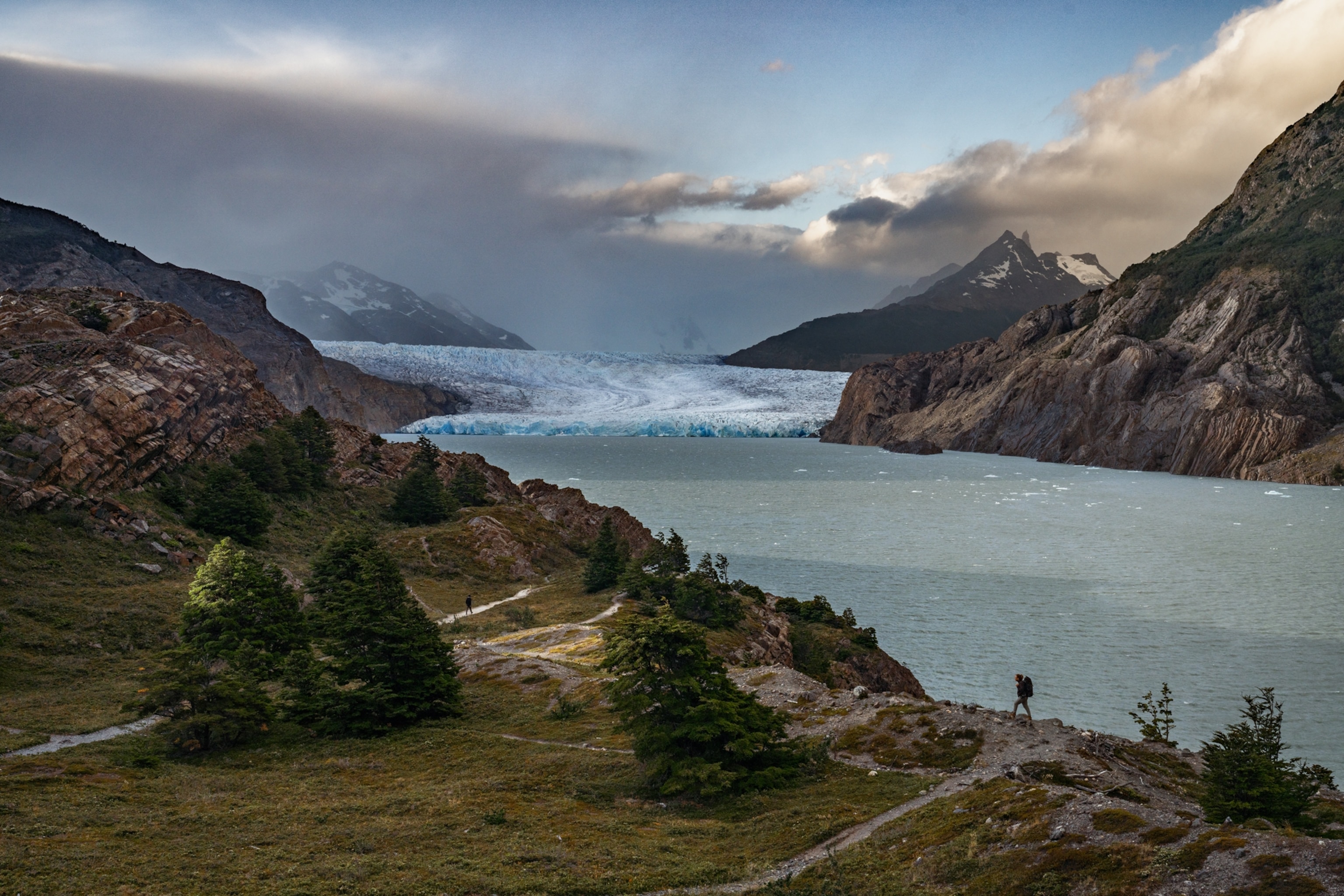 On the vast landscape of the Grey Glacier miniature-looking tourists are seen trekking