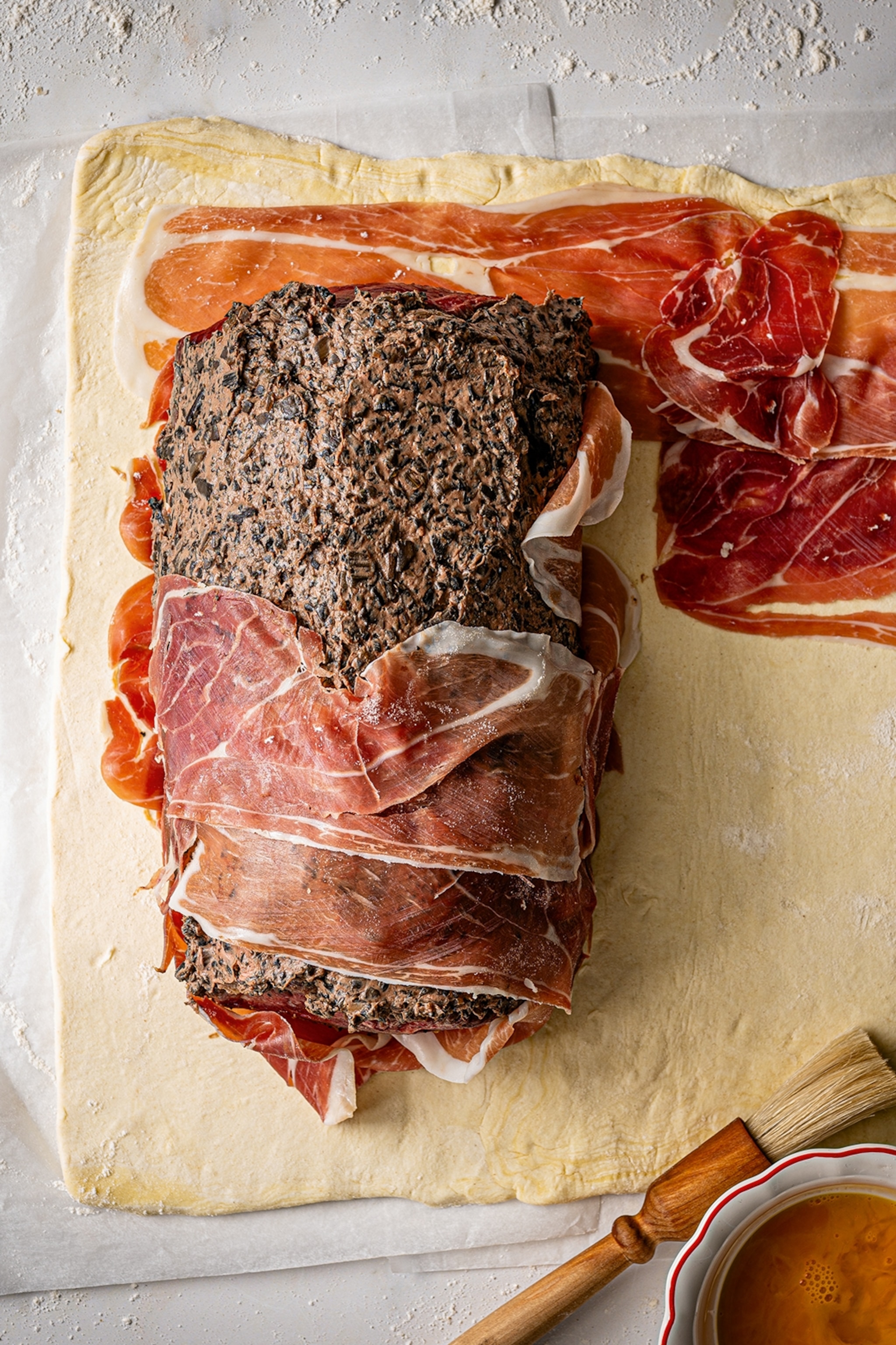 Beef wellington laid on a piece of pastry wrapped in parma ham
