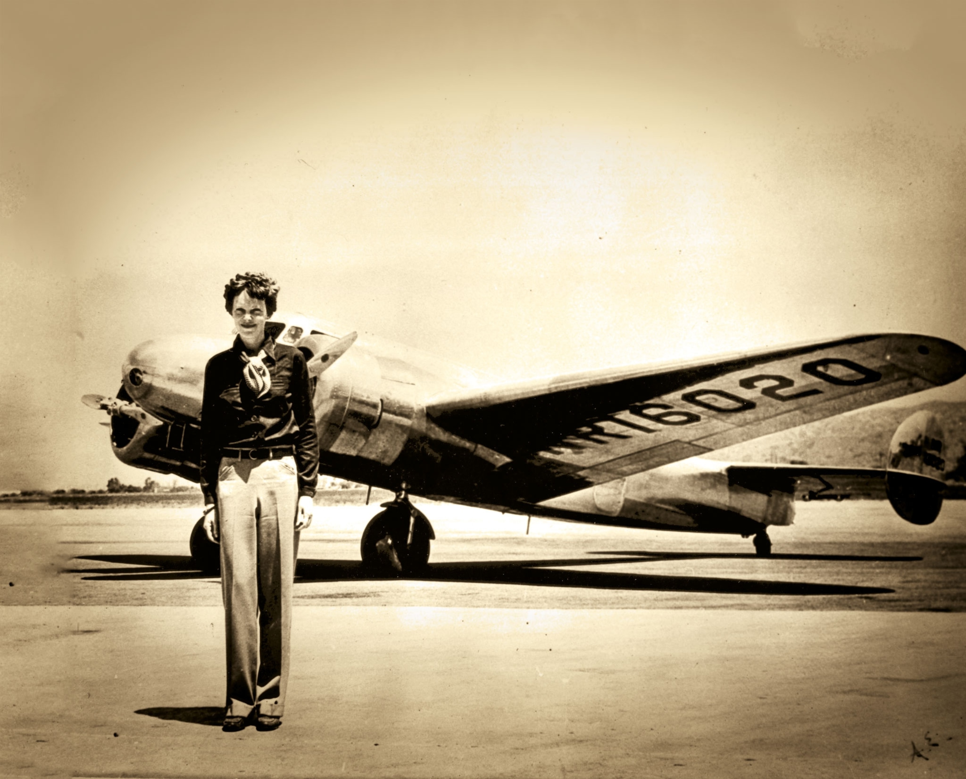 Amelia Earhart standing before her Lockheed Electra