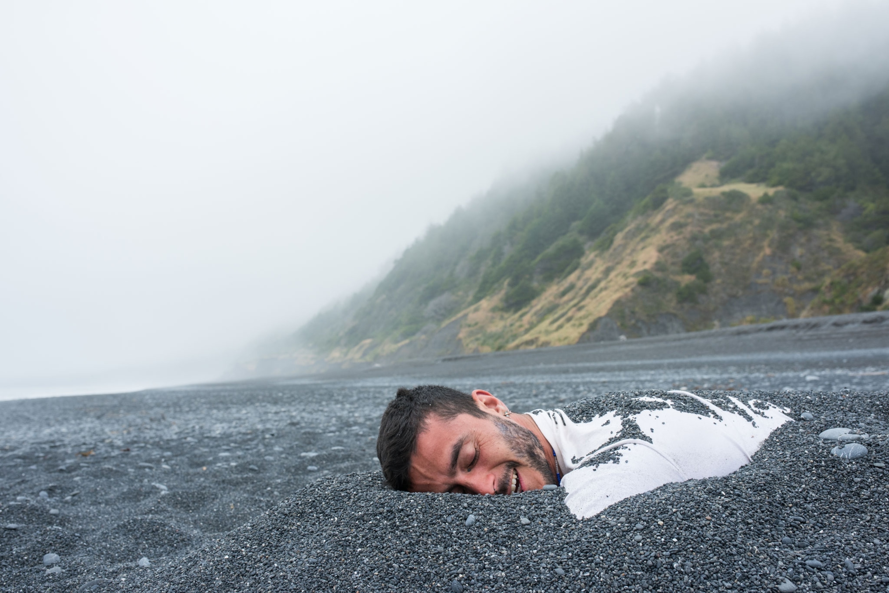 a man is burried in dark rocky sand