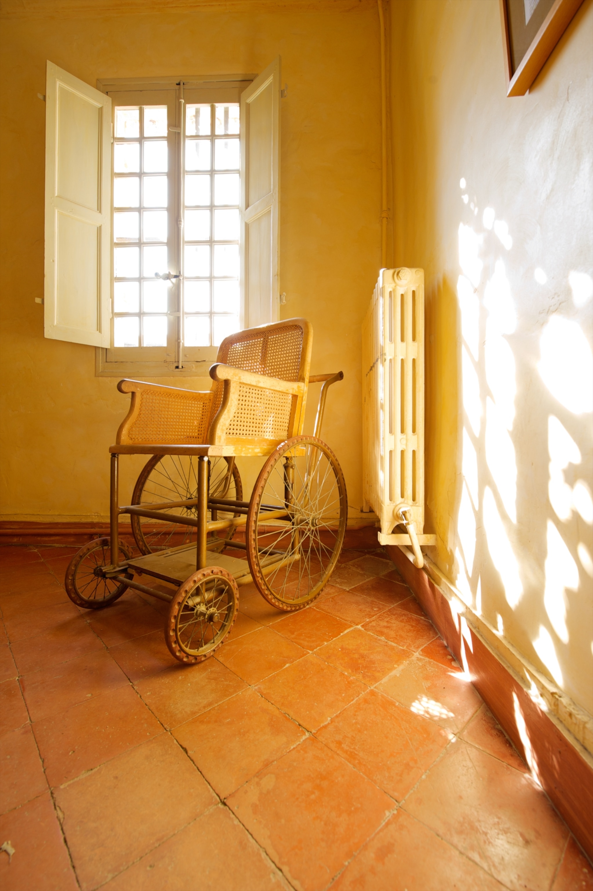 An old wooden wheelchair in a hospital room.