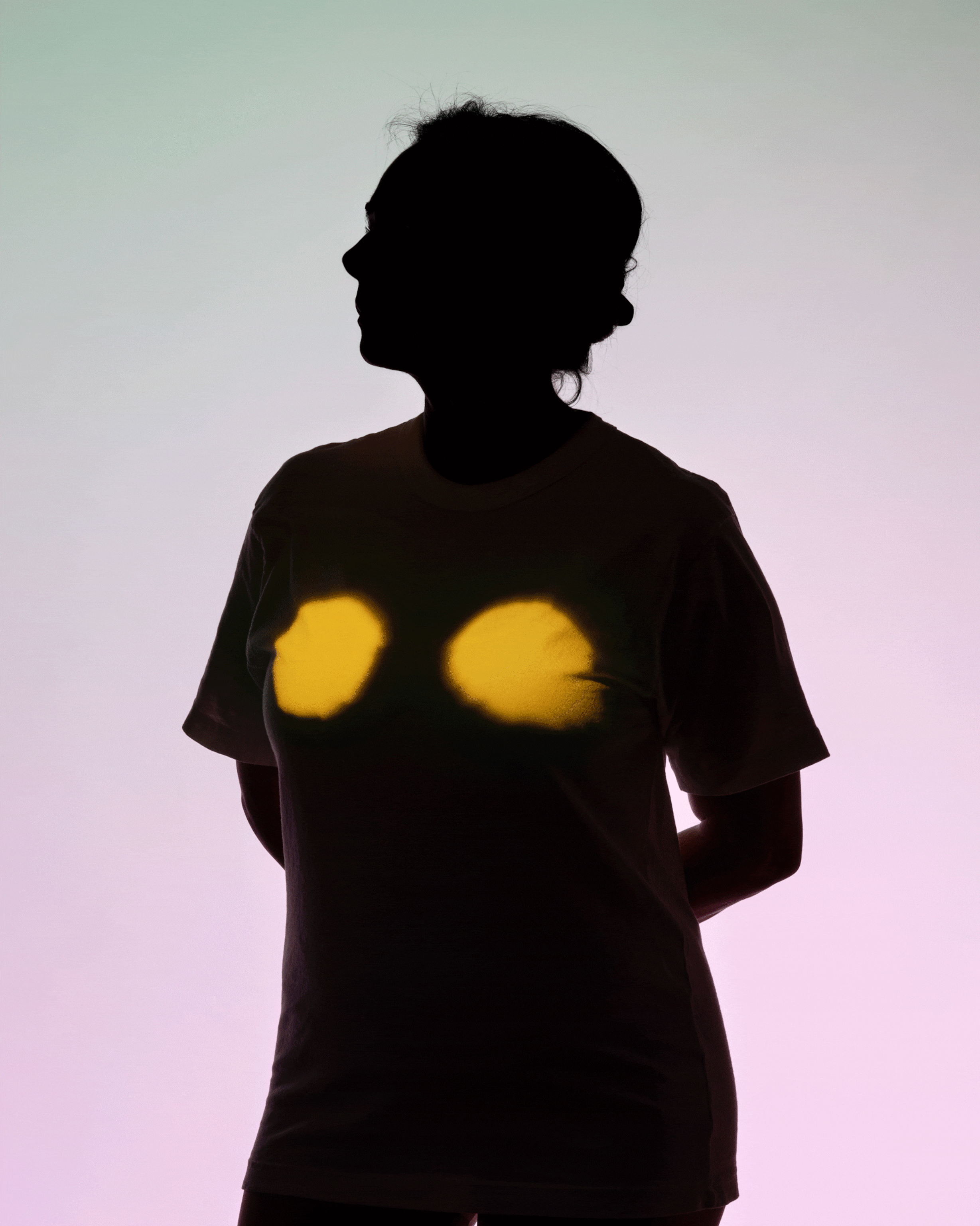 A woman silhouetted against a background that fade from light green to light pink; projections of intestines, breasts, and lungs cycle every second, appearing on the silhouetted woman's body