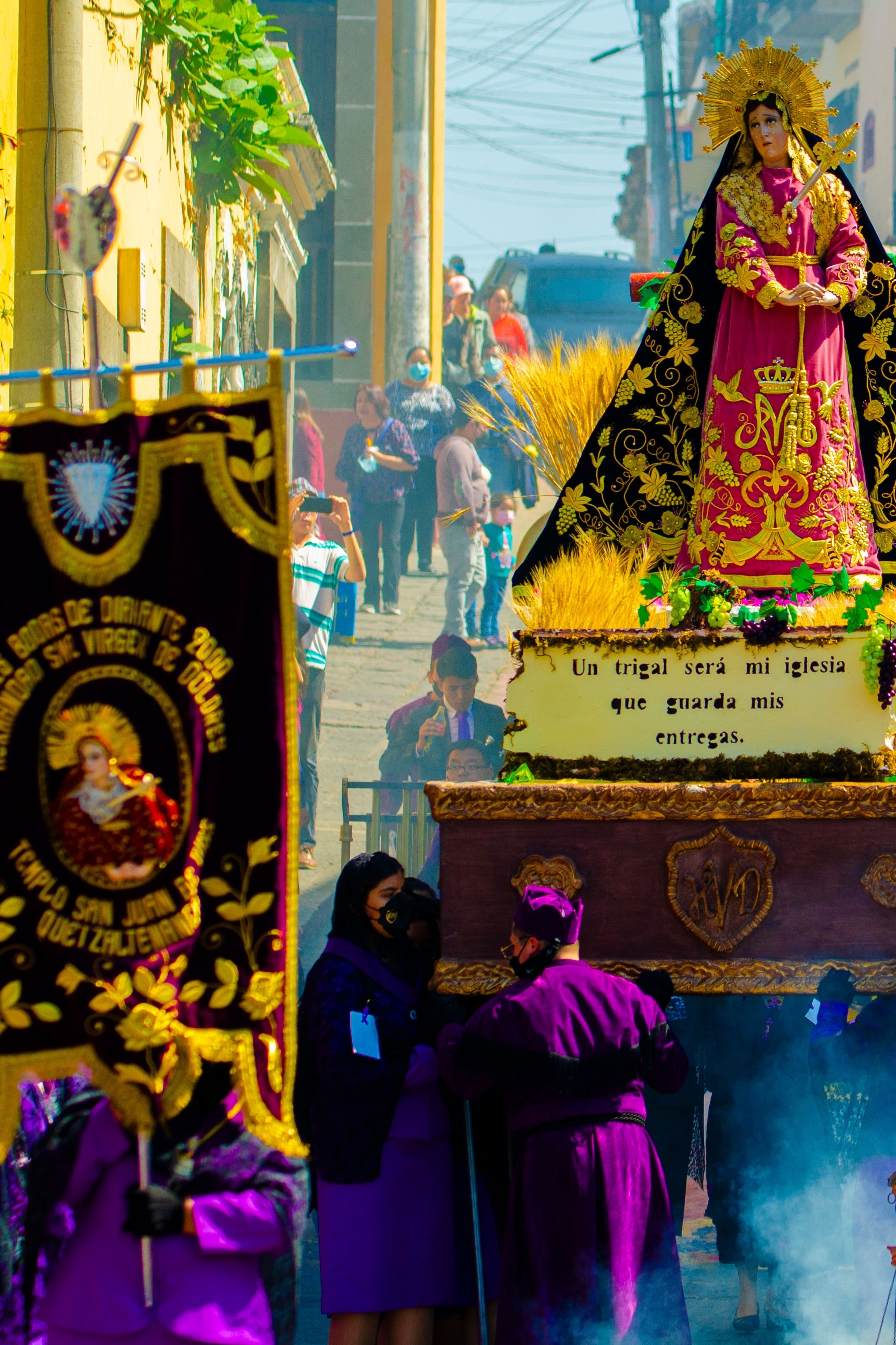 Cucuruchos, devout bearers dressed in long purple tunics and pointed conical hats, carry andas, wooden floats topped with carvings depicting religious figures.