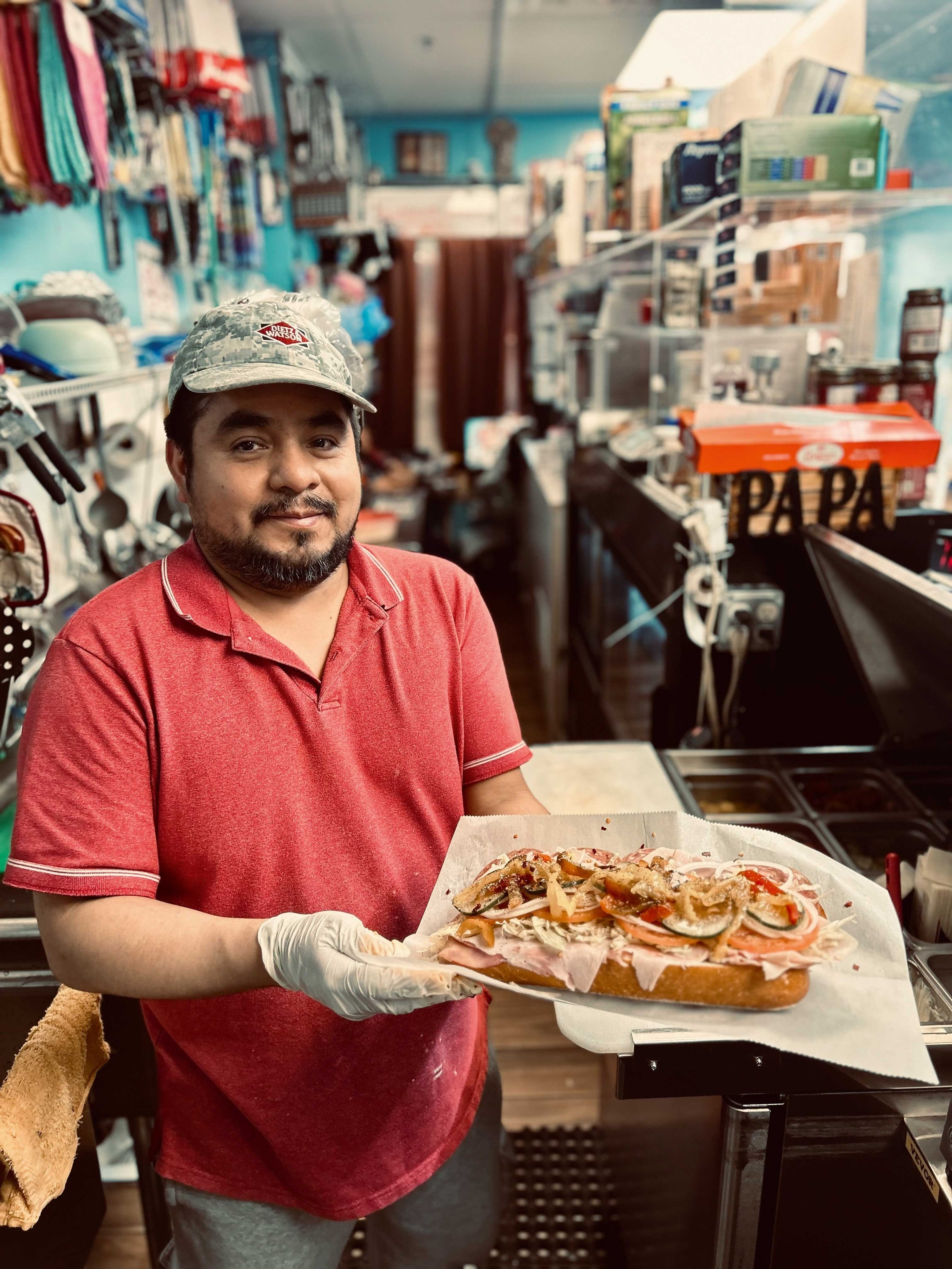 A chef holds a large hoagie sandwich