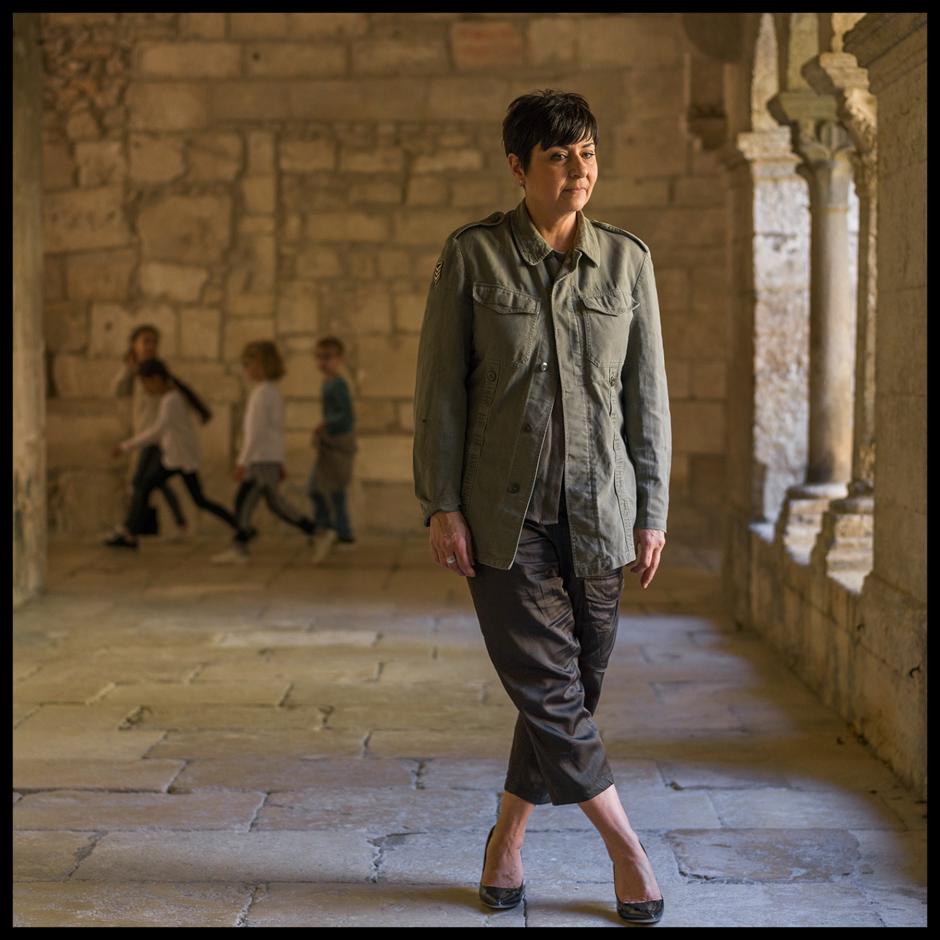 a woman standing along a hallway near windows