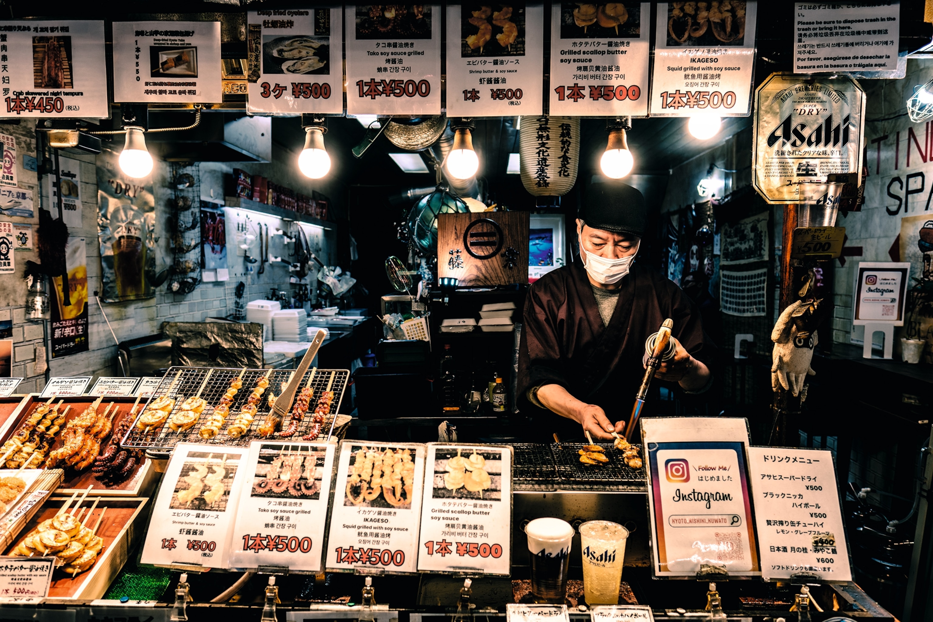 A vendor cooking skewers at his food stall in Nishiki Market.
