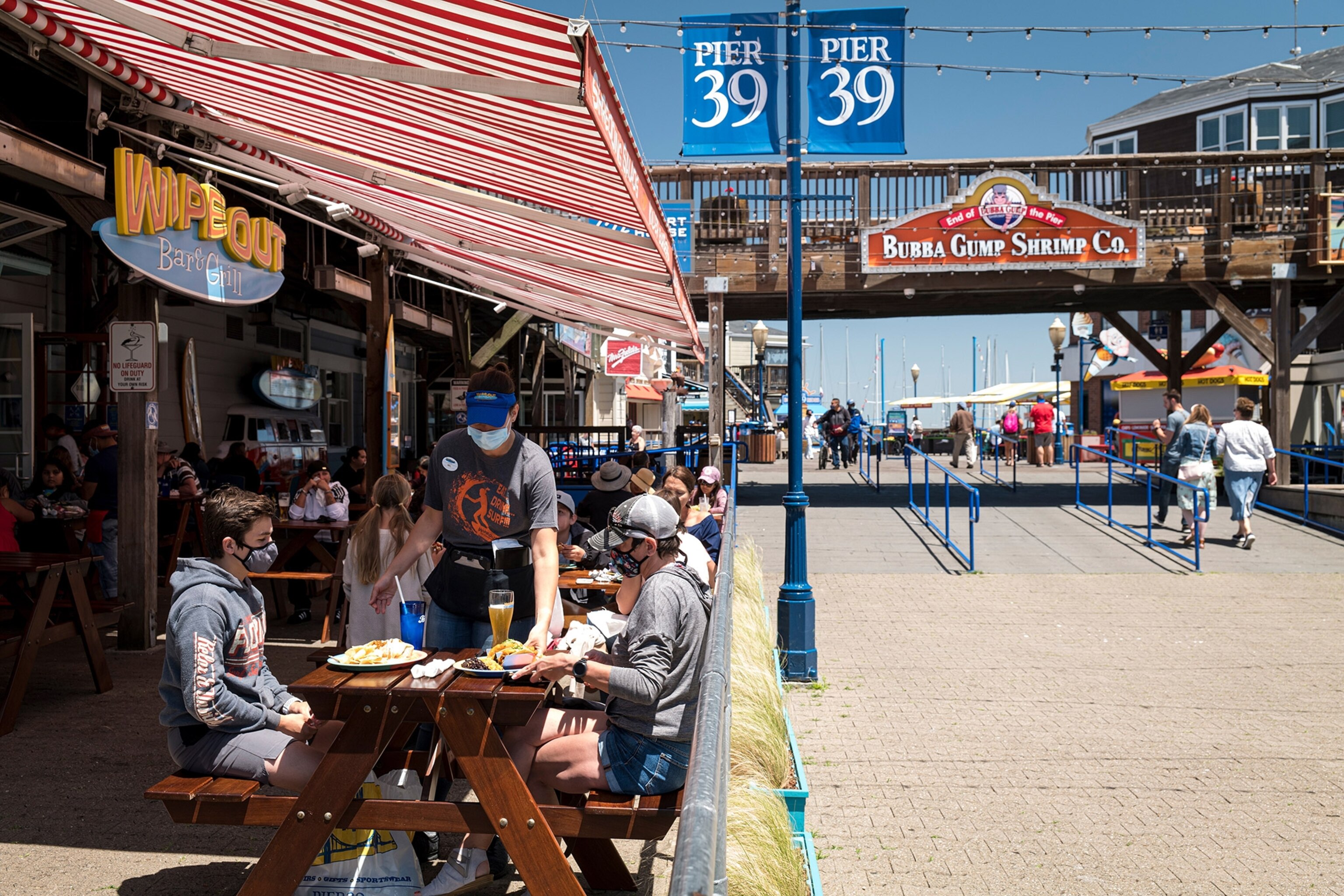 a server delivering plates of food to customers seated outside at Fisherman's Wharf