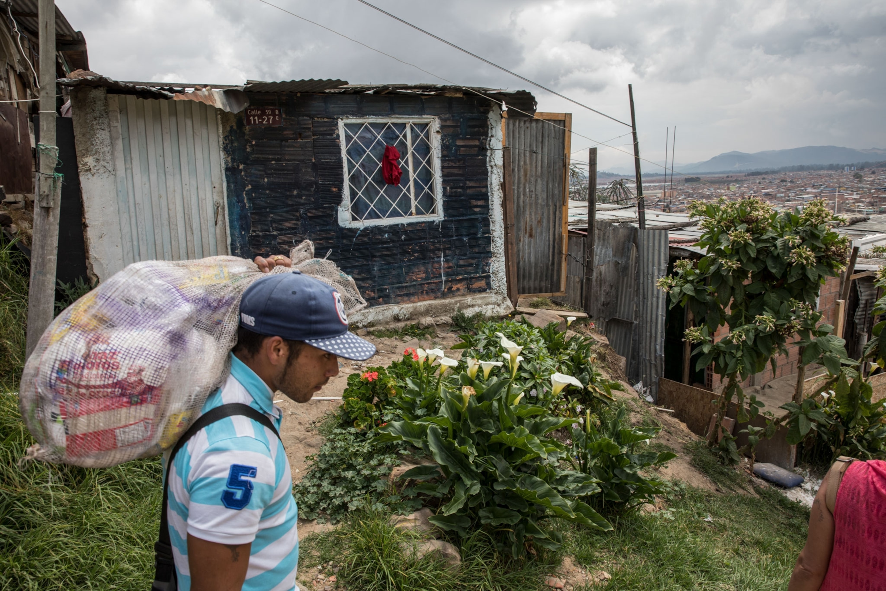 a man carrying food to his house in one of the poorest neighborhoods in Bogota