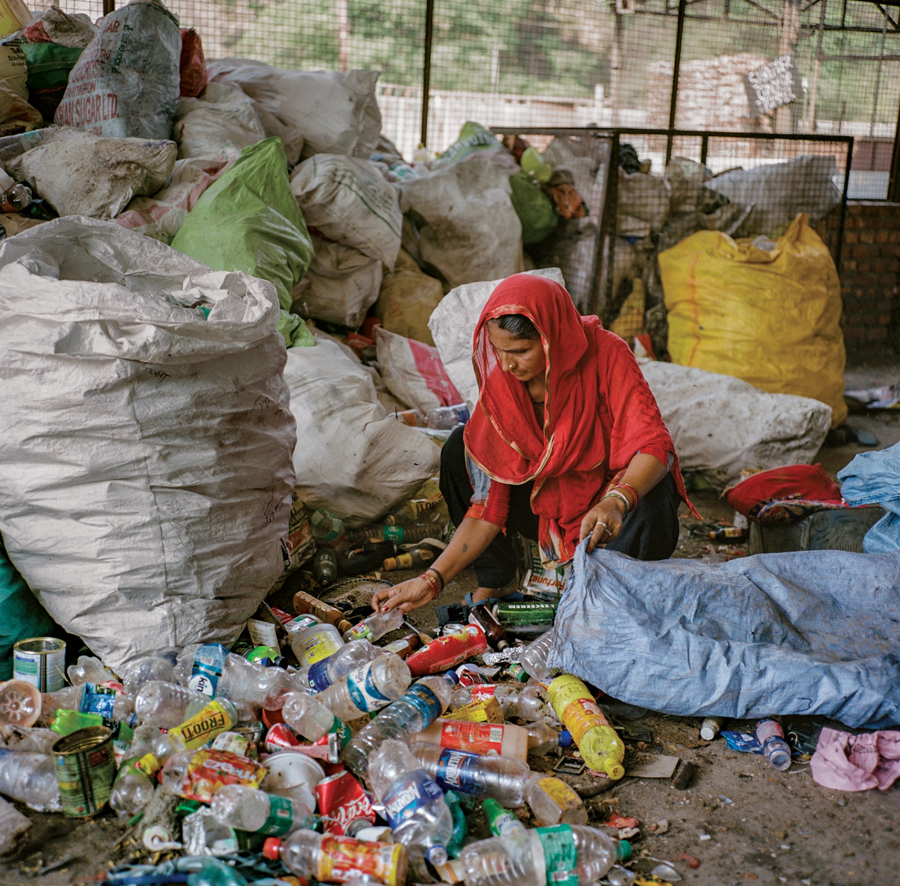 Picture of woman in red headscarf putting plastic bottles into large bag.