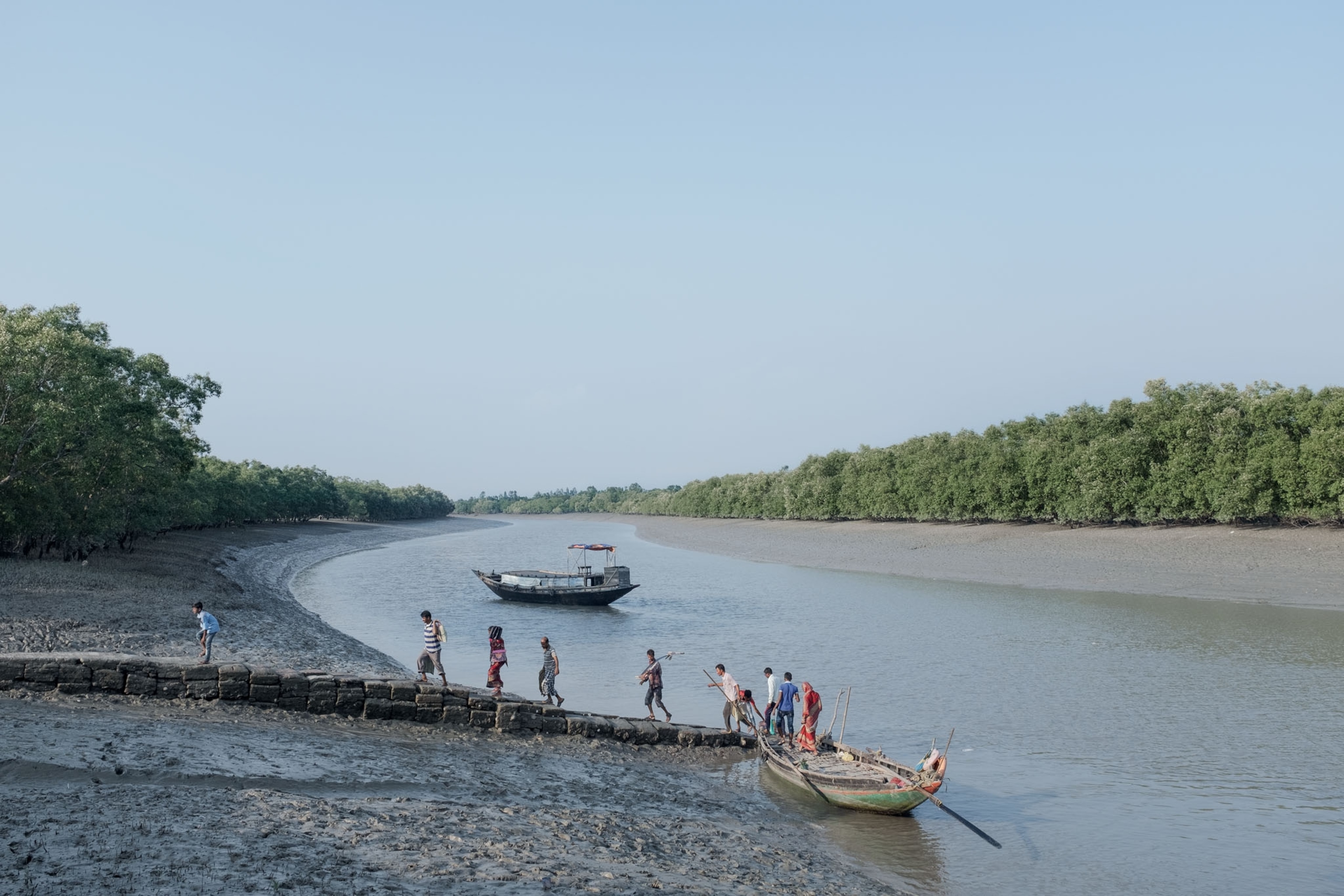 people walking towards the shore on the banks of a river