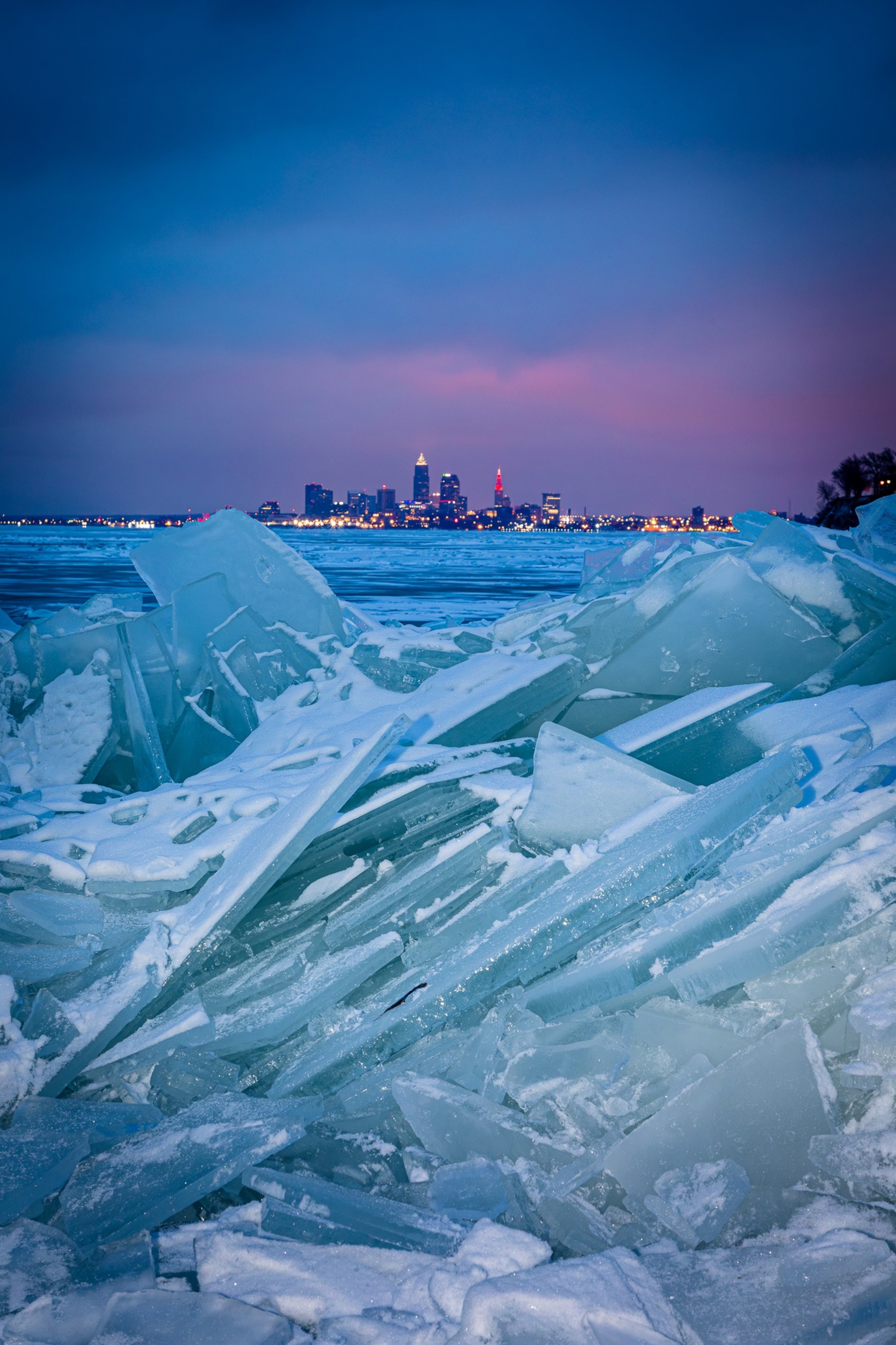 The Cleveland skyline in the distance at sunset surrounded by an icy Lake Erie.