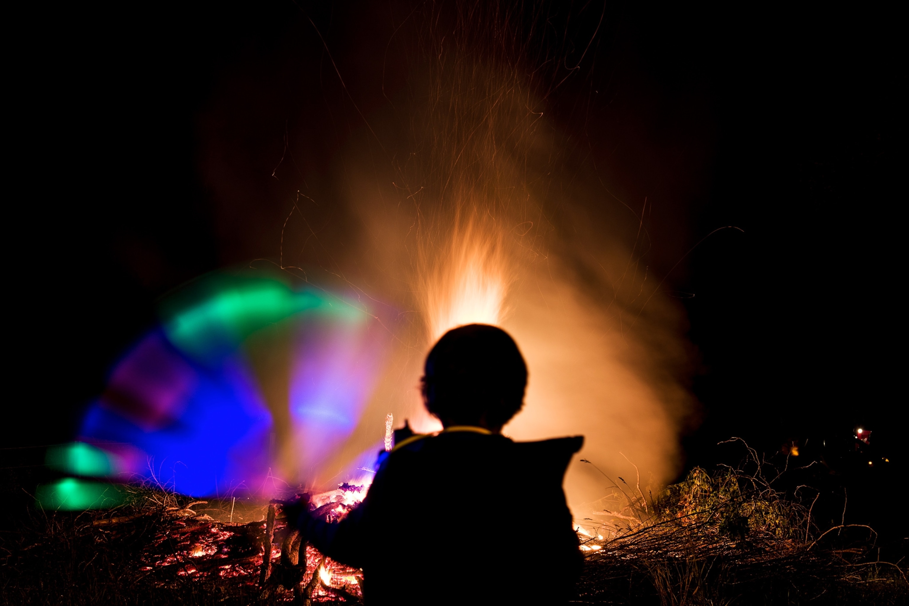 a boy playing with a glow stick during summer solstice celebrations in Busbach, Germany
