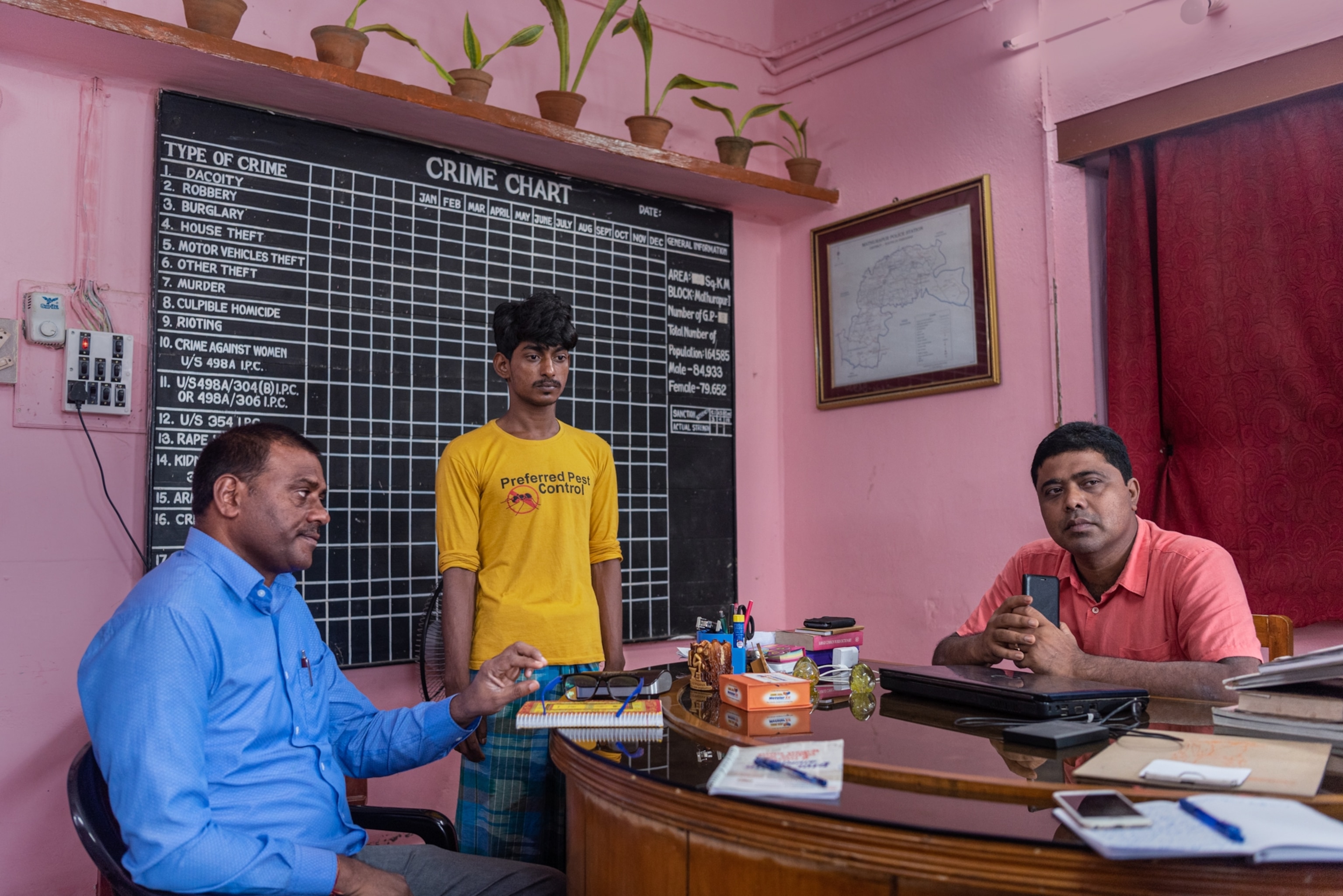 three people sitting in a police office having a conversation