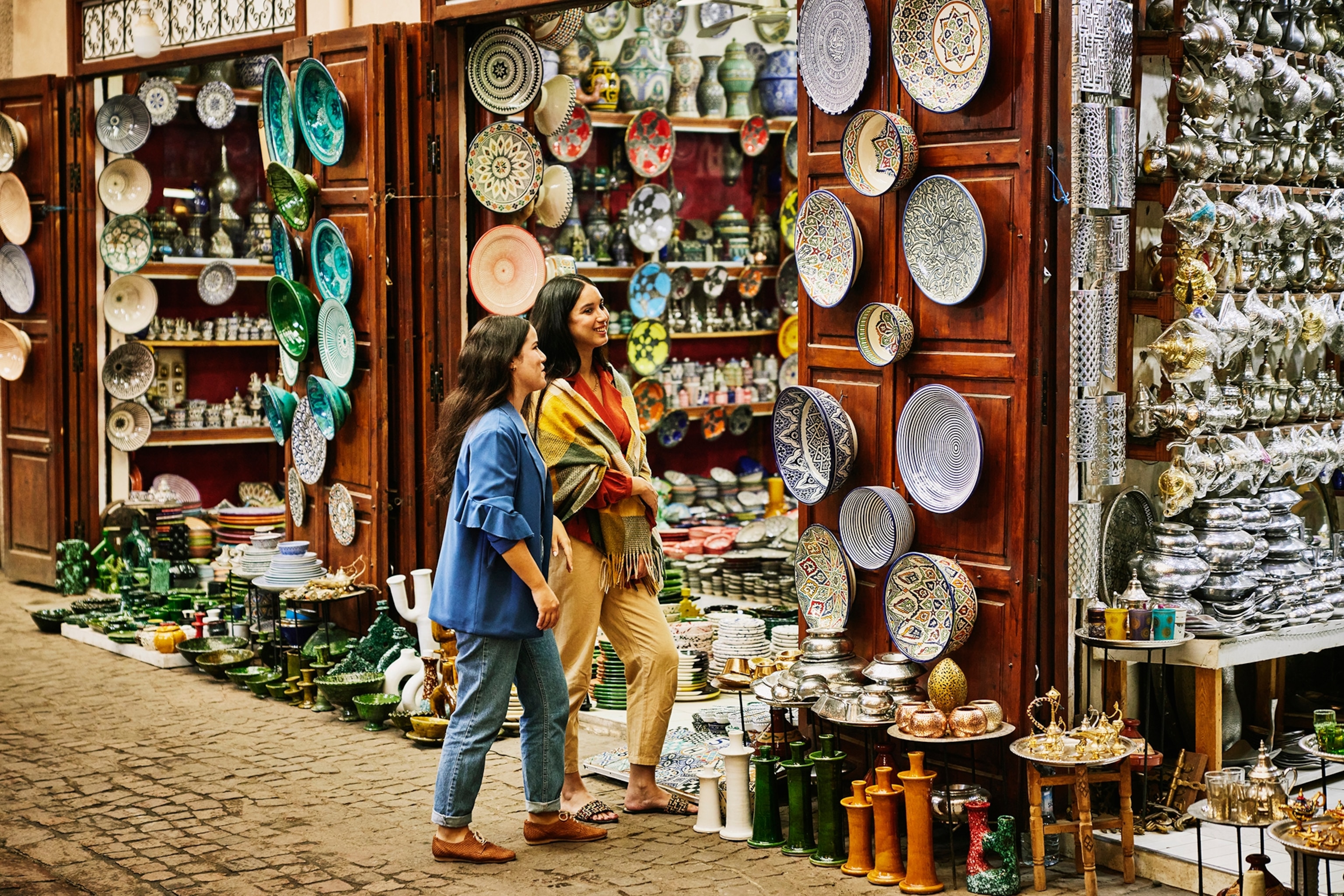 Two young women standing at a traditional hand painted crockery stall in Marrakech