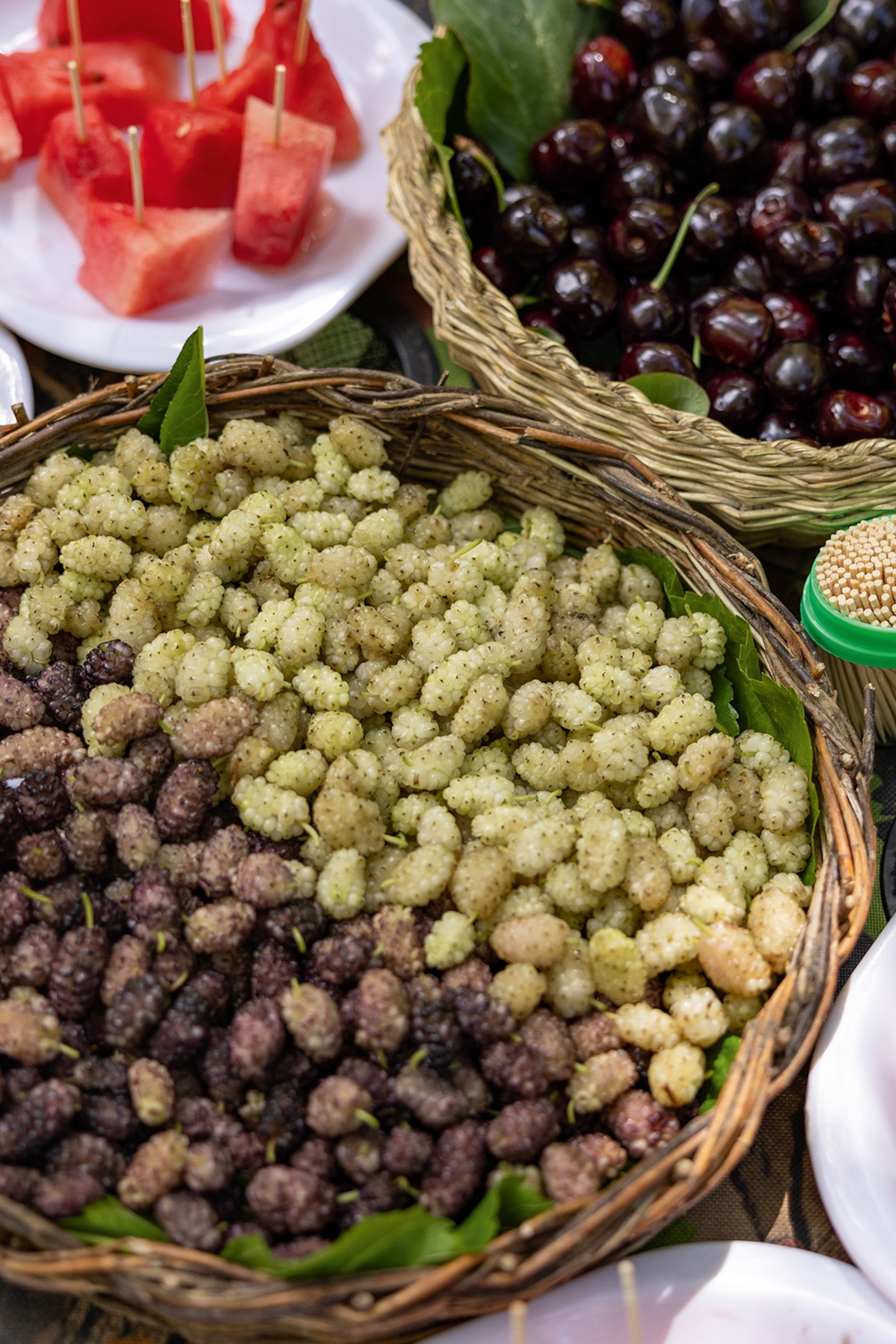 A spread of mulberries, cherries and watermelon laid out nicely on a table.