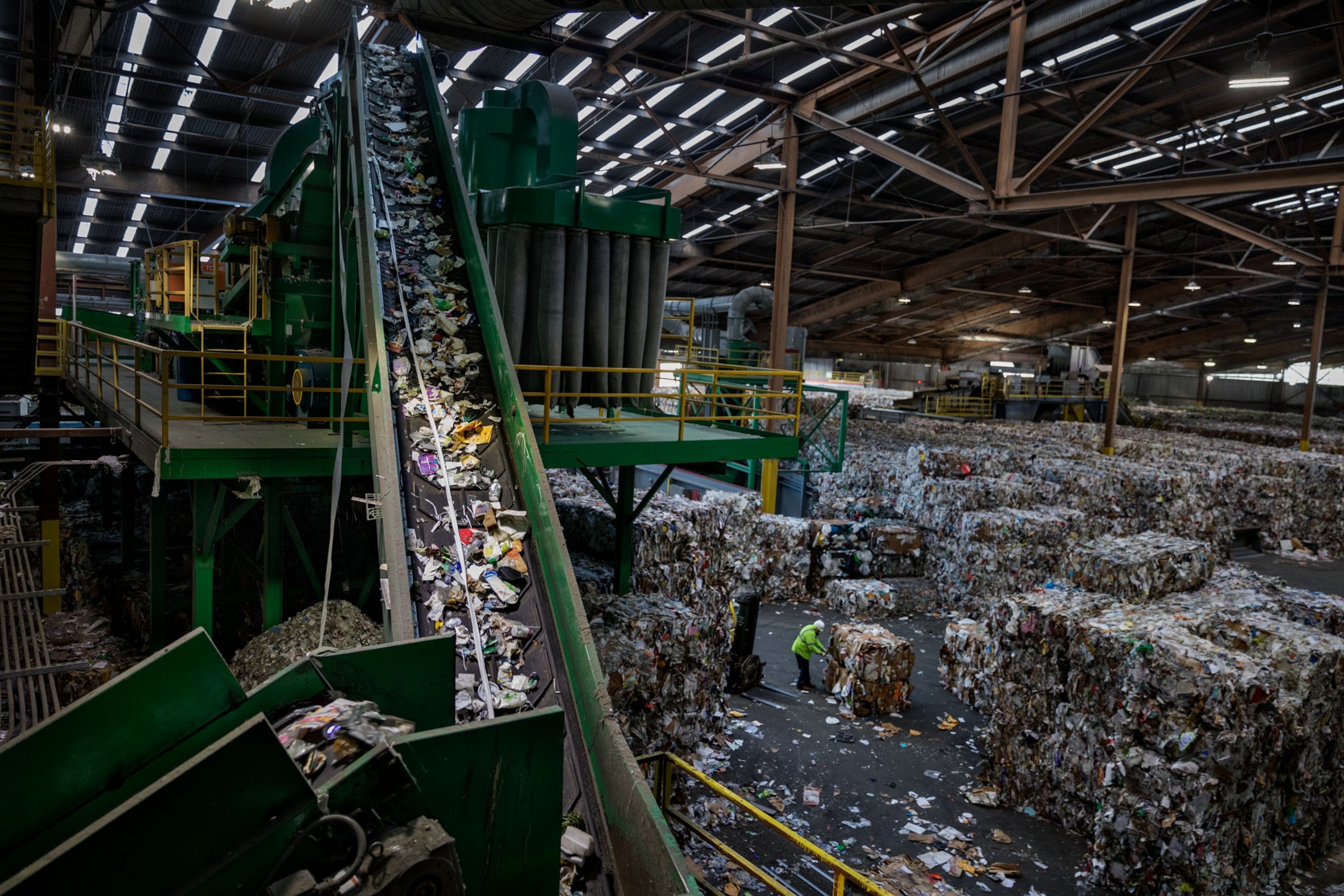 a conveyor belt in large recycling plant filled with tons of plastic waste