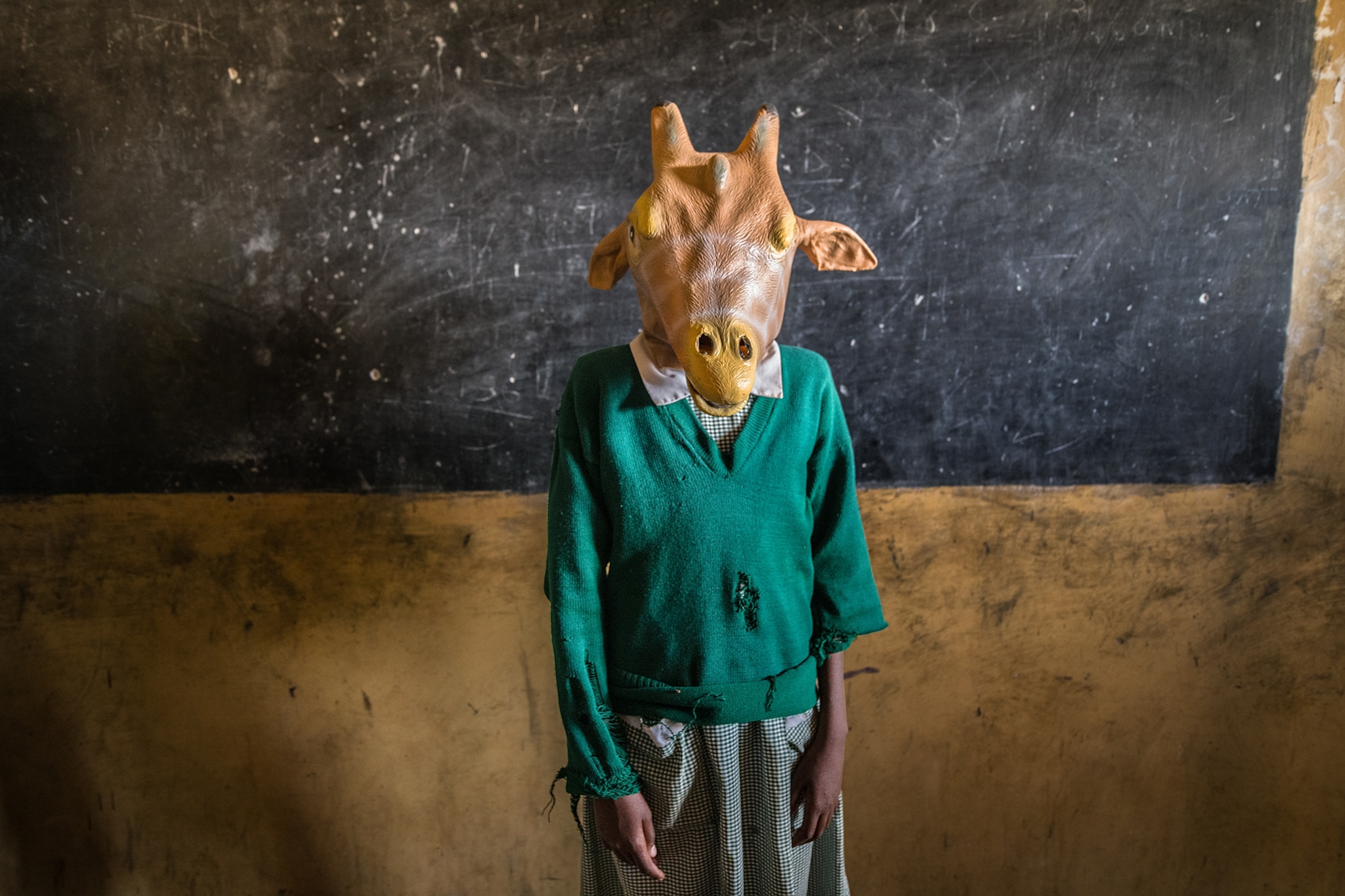 a student wearing a giraffe mask while a giraffe conservation team visited her school