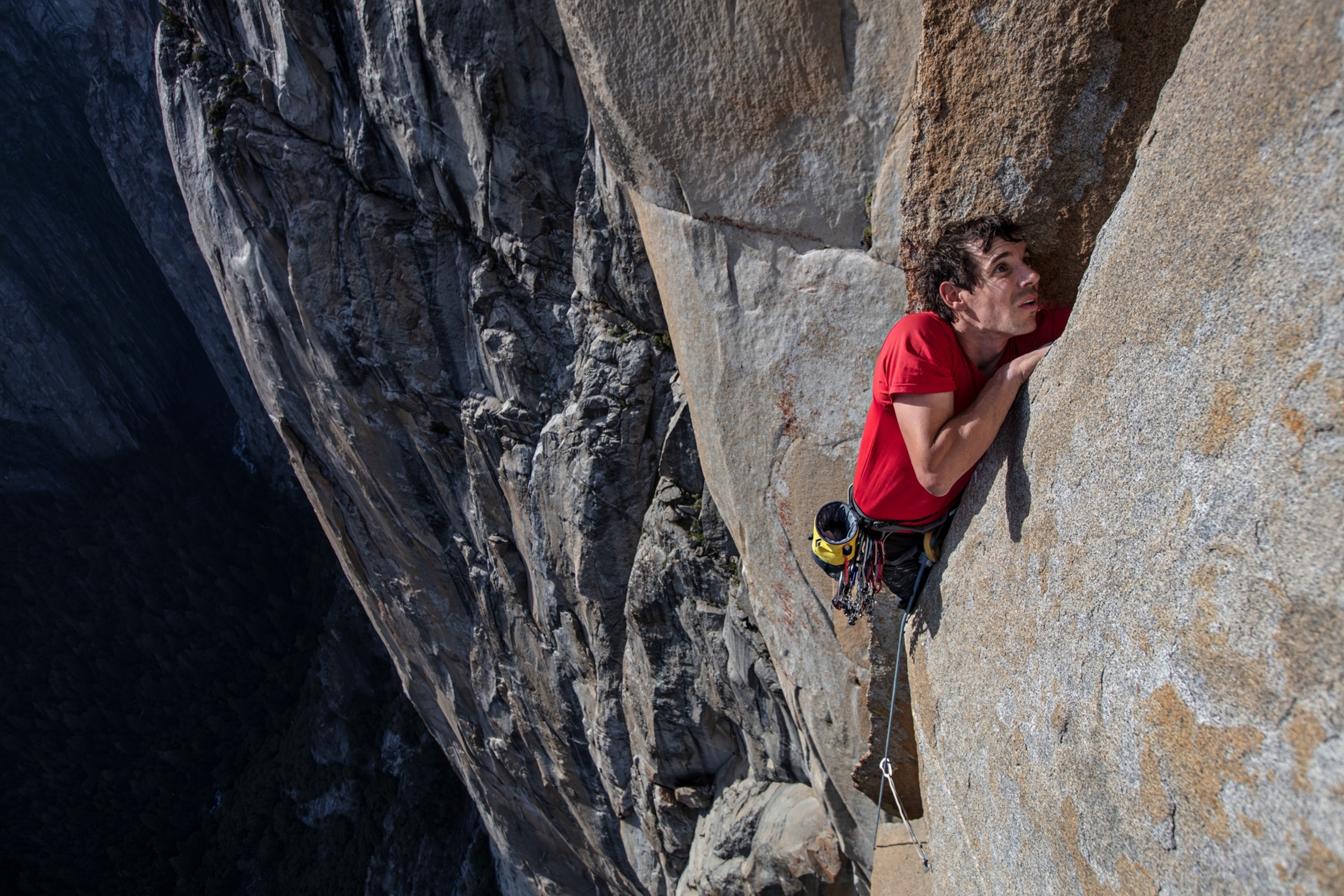 a man in the crack in the vertical wall of the mountain