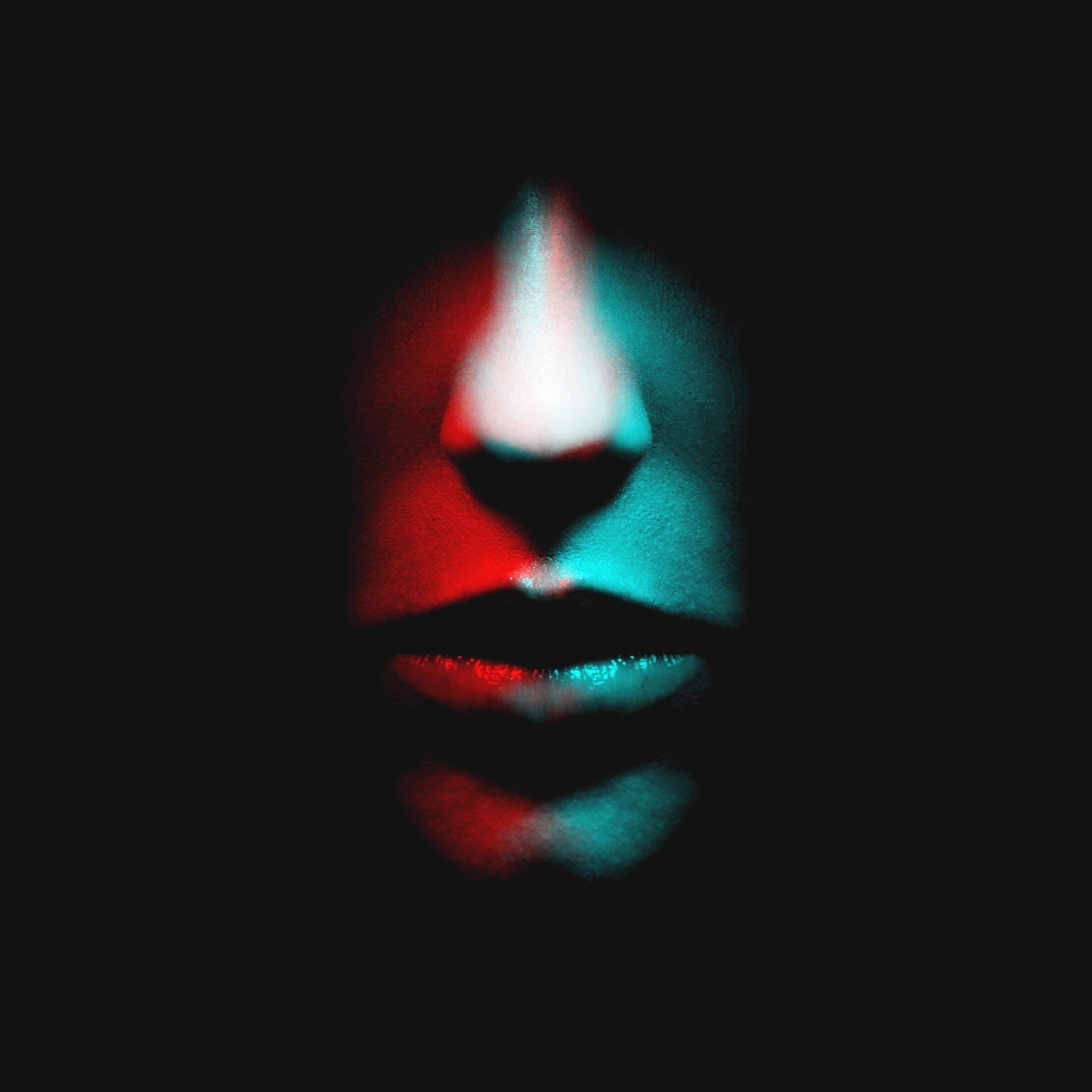 Someone's nose and mouth lit by a red light from the left and a blue light from the right.