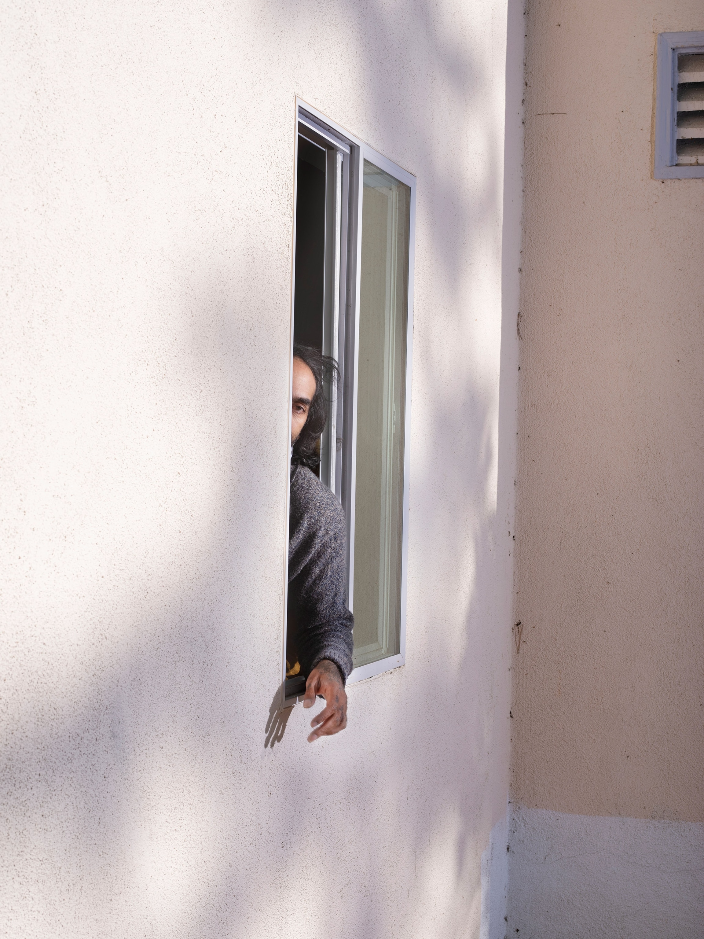 a man reaching his hand out of his window